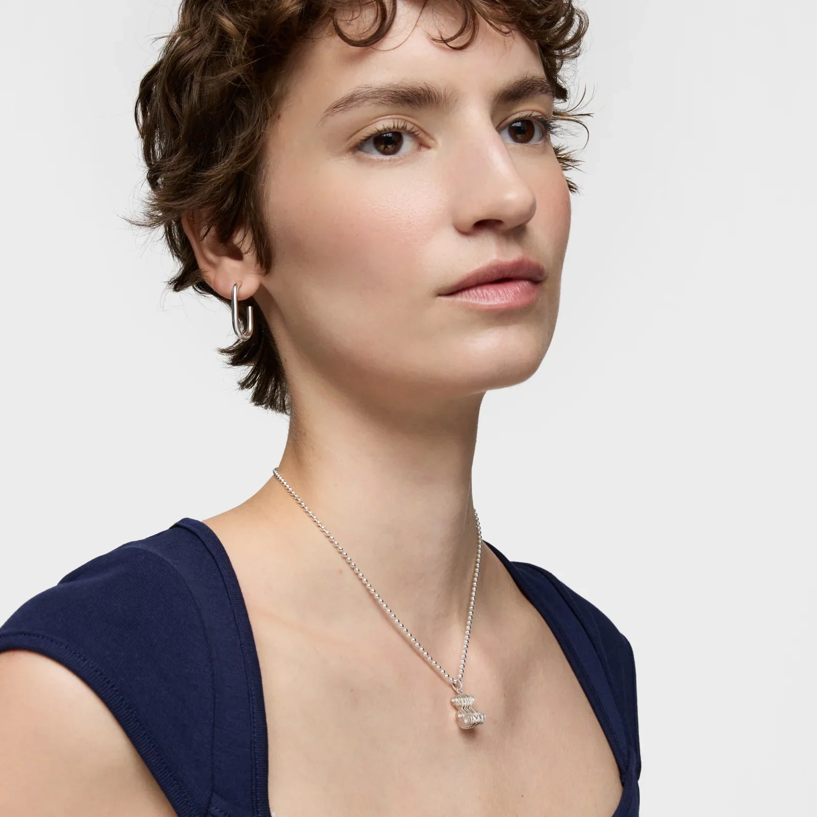 דוגמנית עונדת שרשרת כסף תליון ועגיל עגול, רקע לבן, אופנת תכשיטים CHOZEN