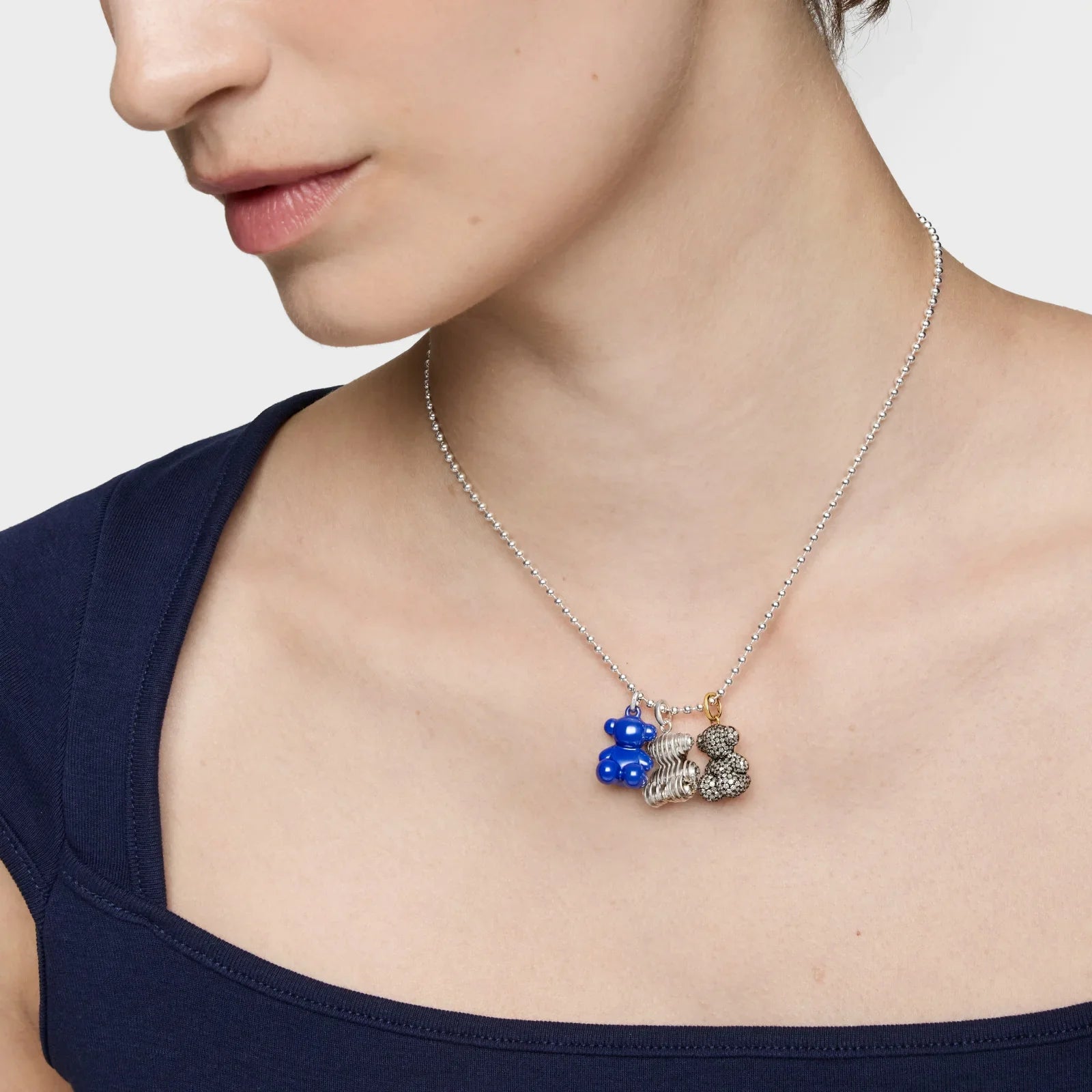 שרשרת כדורים עם שלושה תליונים מעוצבים, כולל דוב כחול, על צוואר אישה, CHOZEN
