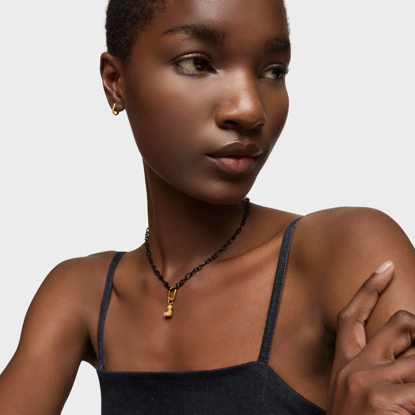 דוגמנית עונדת שרשרת תליון זהוב ואוזן עם עגיל קטן, רקע אפור, CHOZEN, תכשיטי אופנה יוקרתיים