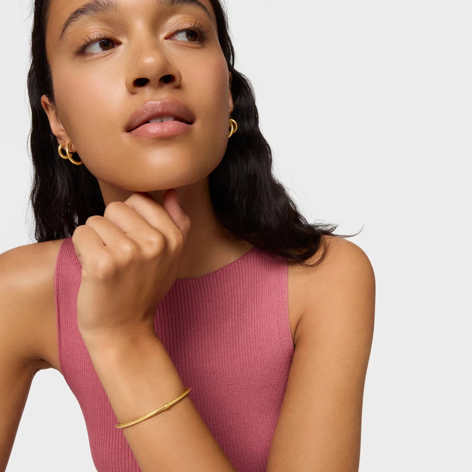 אישה עם עגילי זהב וצמיד זהב, לובשת גופיה ורודה, צילום תדמית לאופנה CHOZEN