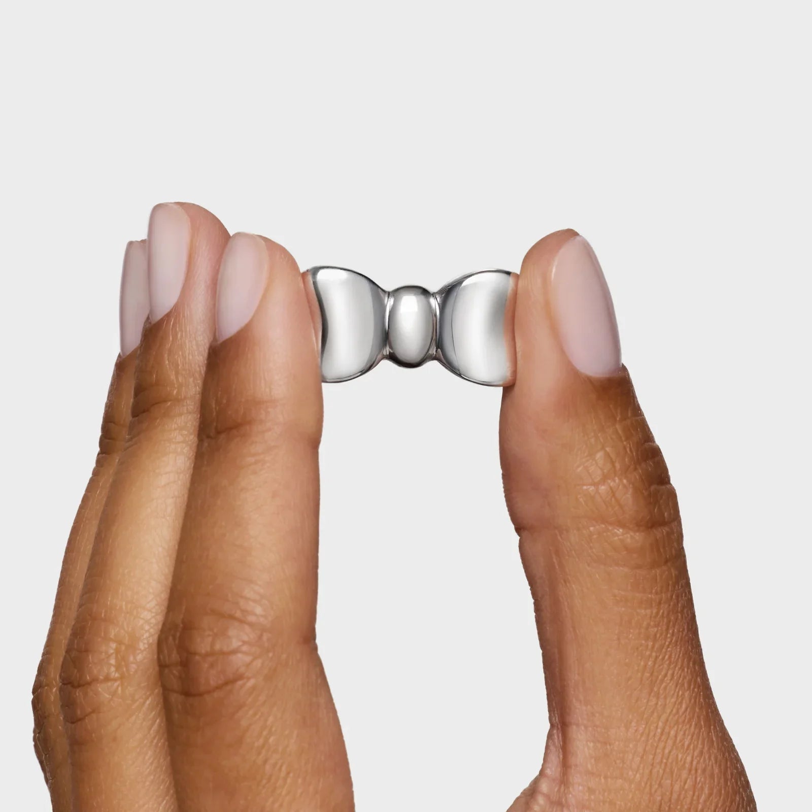 ידיים מחזיקות קליפס כסוף קטן יוקרתי מצולם מקרוב על רקע לבן, מבית CHOZEN