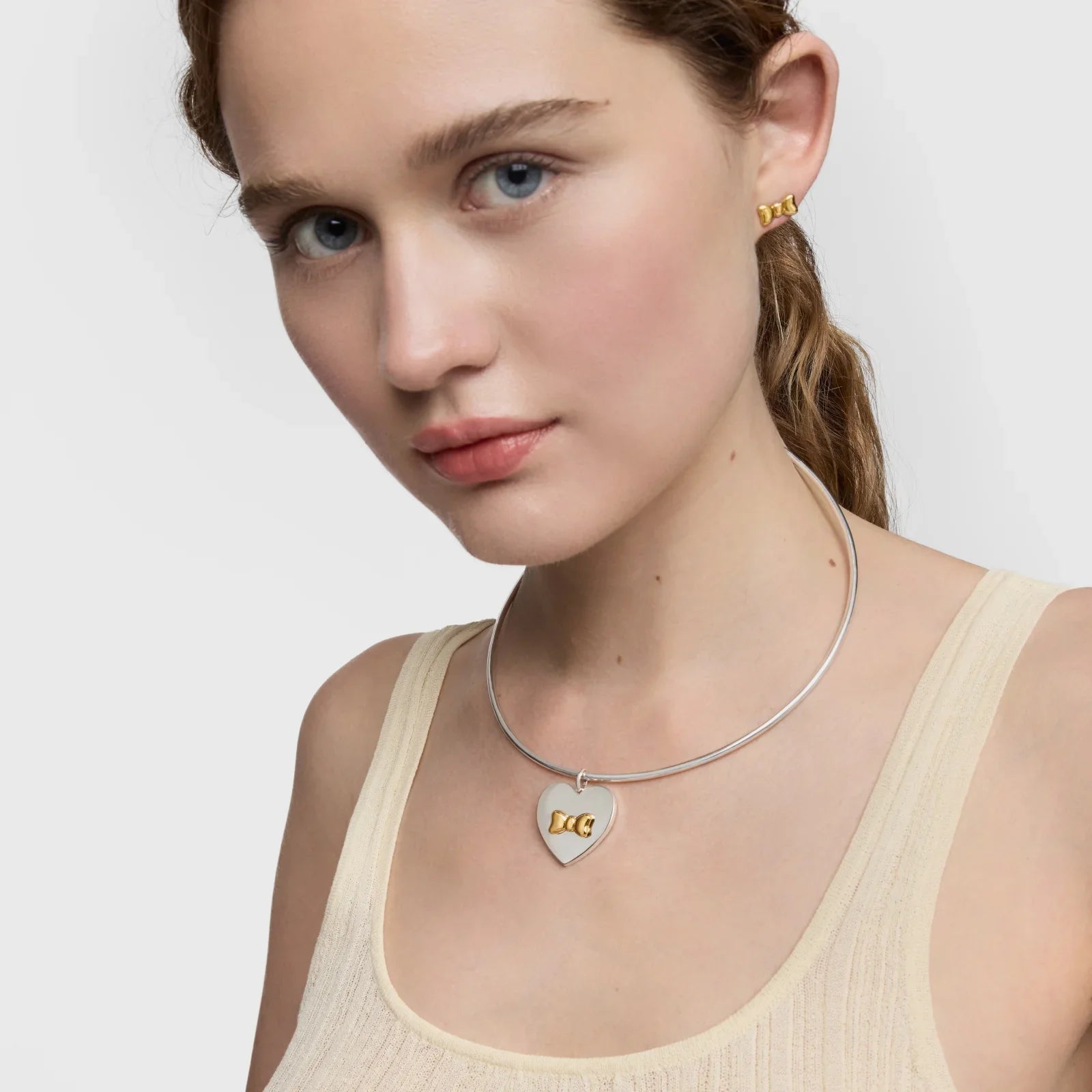 דוגמנית עונדת שרשרת כסף עם תליון לב ועגילי זהב, צילום קמפיין מותגי תכשיטים ב-CHOZEN