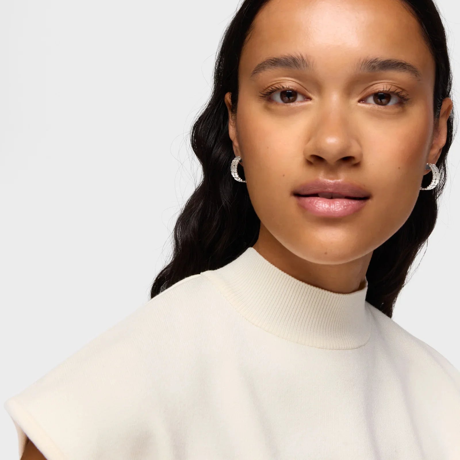 אישה עם עגילי חישוק כסף, לובשת חולצה לבנה, צילום לאתר CHOZEN מותגים מובילים