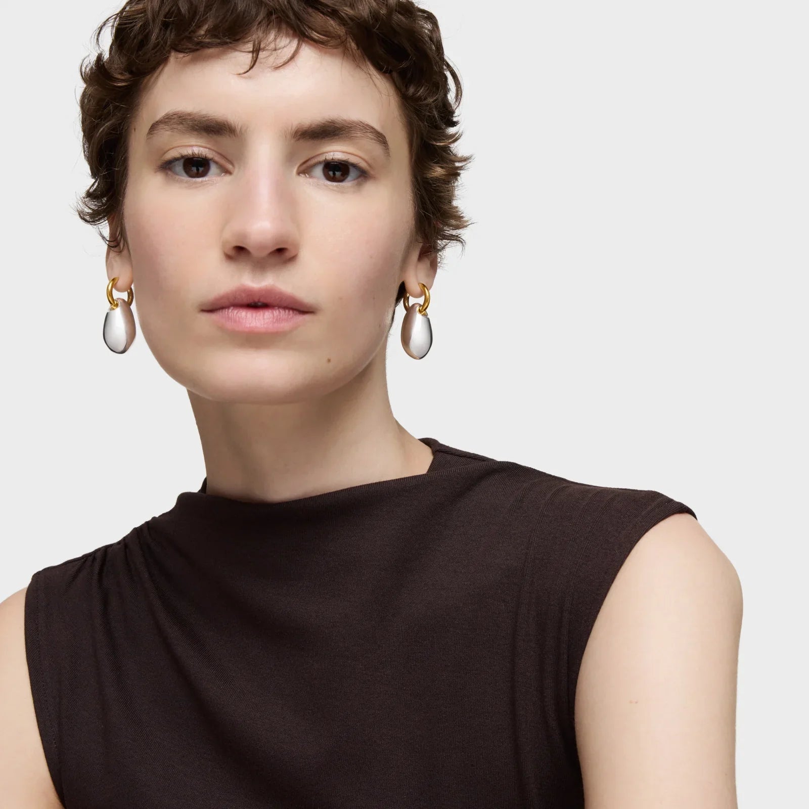 אישה עם שיער קצר עונדת עגילי זהב עם תליון פנינה, צילום תכשיטים יוקרתי באתר CHOZEN