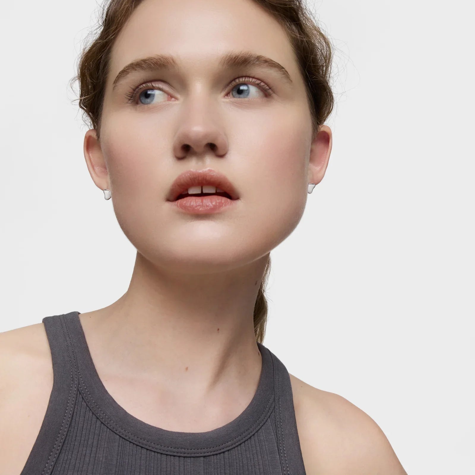 אישה צעירה בחולצה אפורה, מבט הצידה, צילום תדמית לחנות CHOZEN