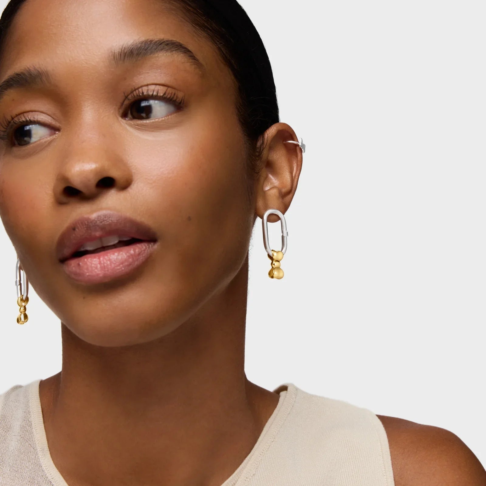 אישה עונדת עגילי זהב וכסף מעוצבים, צילום תקריב, מותגי תכשיטים CHOZEN