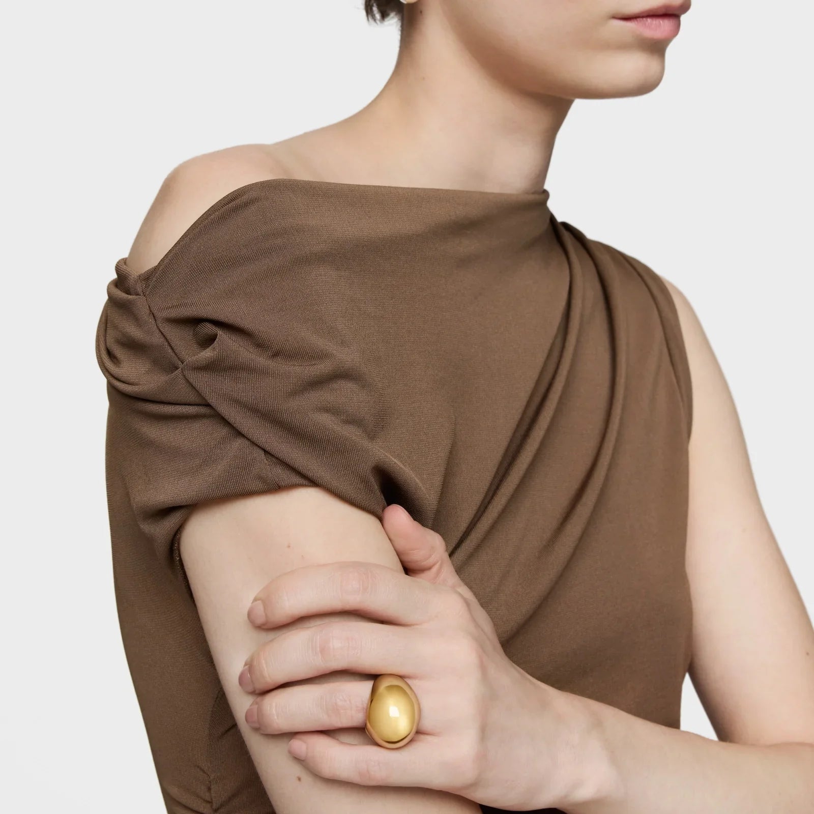 אישה לובשת חולצה חומה עם שרוול שמוט וטבעת זהב גדולה, אופנה יוקרתית מבית CHOZEN