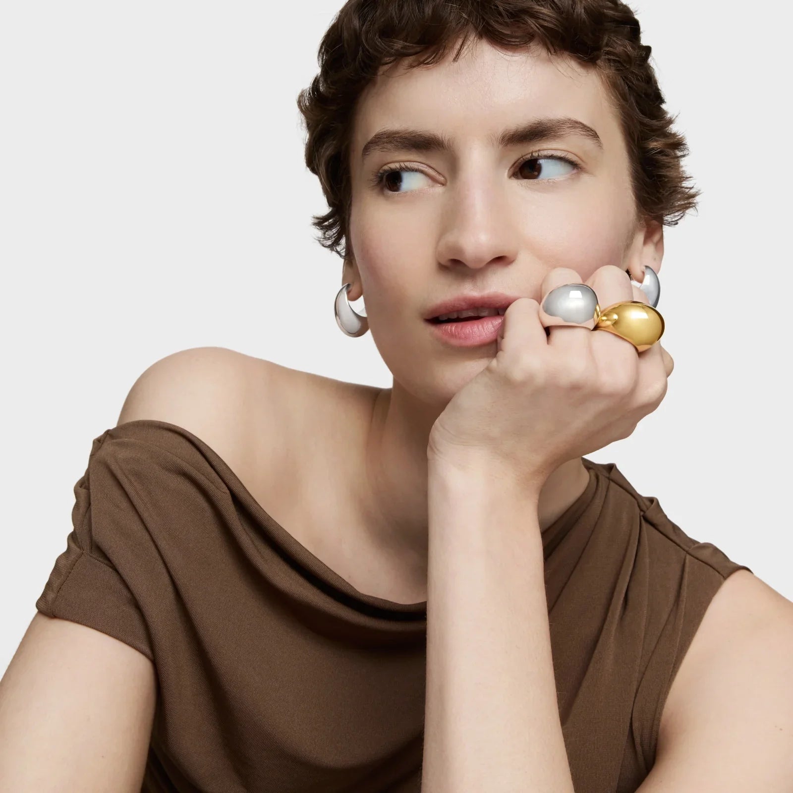 דוגמנית עם חולצה חומה עונדת עגילים טבעת כסף וזהב, תכשיטים יוקרתיים CHOZEN