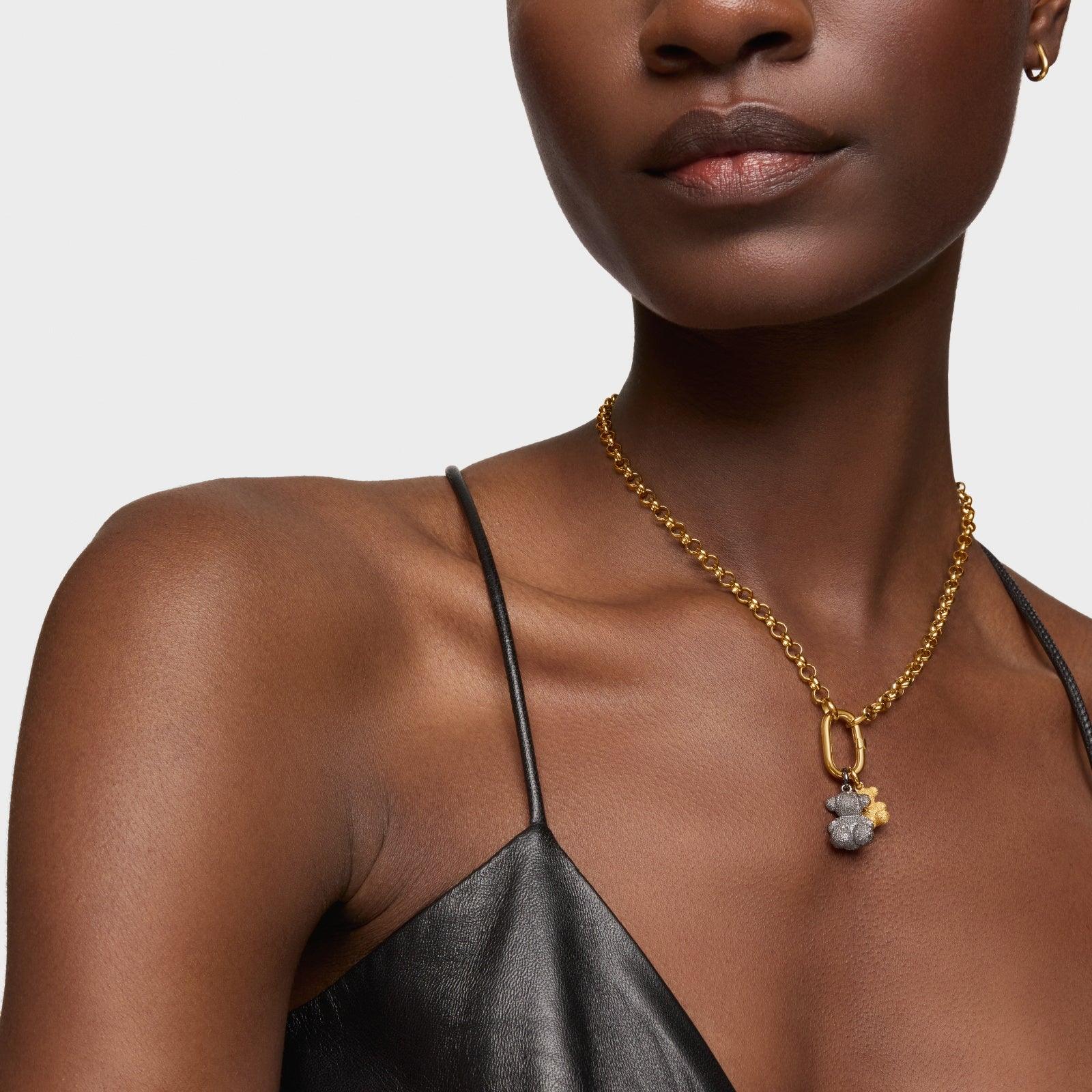 דוגמנית עם שמלת עור שחורה ועונדת שרשרת זהב עם תליון אופנתי, CHOZEN מותגים מובילים