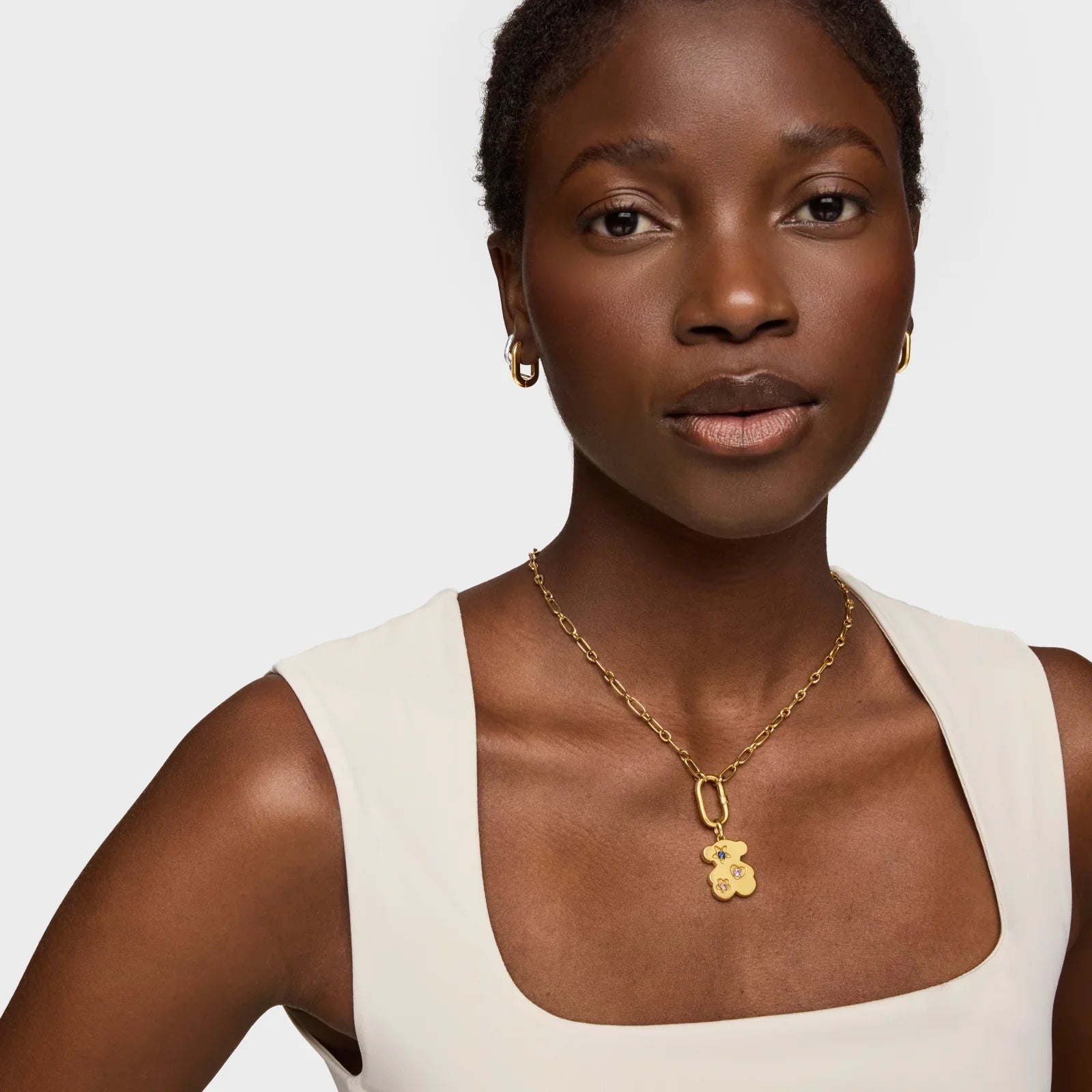 דוגמנית עם שרשרת זהב תליון דוב, עגילי זהב, שמלה לבנה, צולם ל-CHOZEN מותגים מובילים