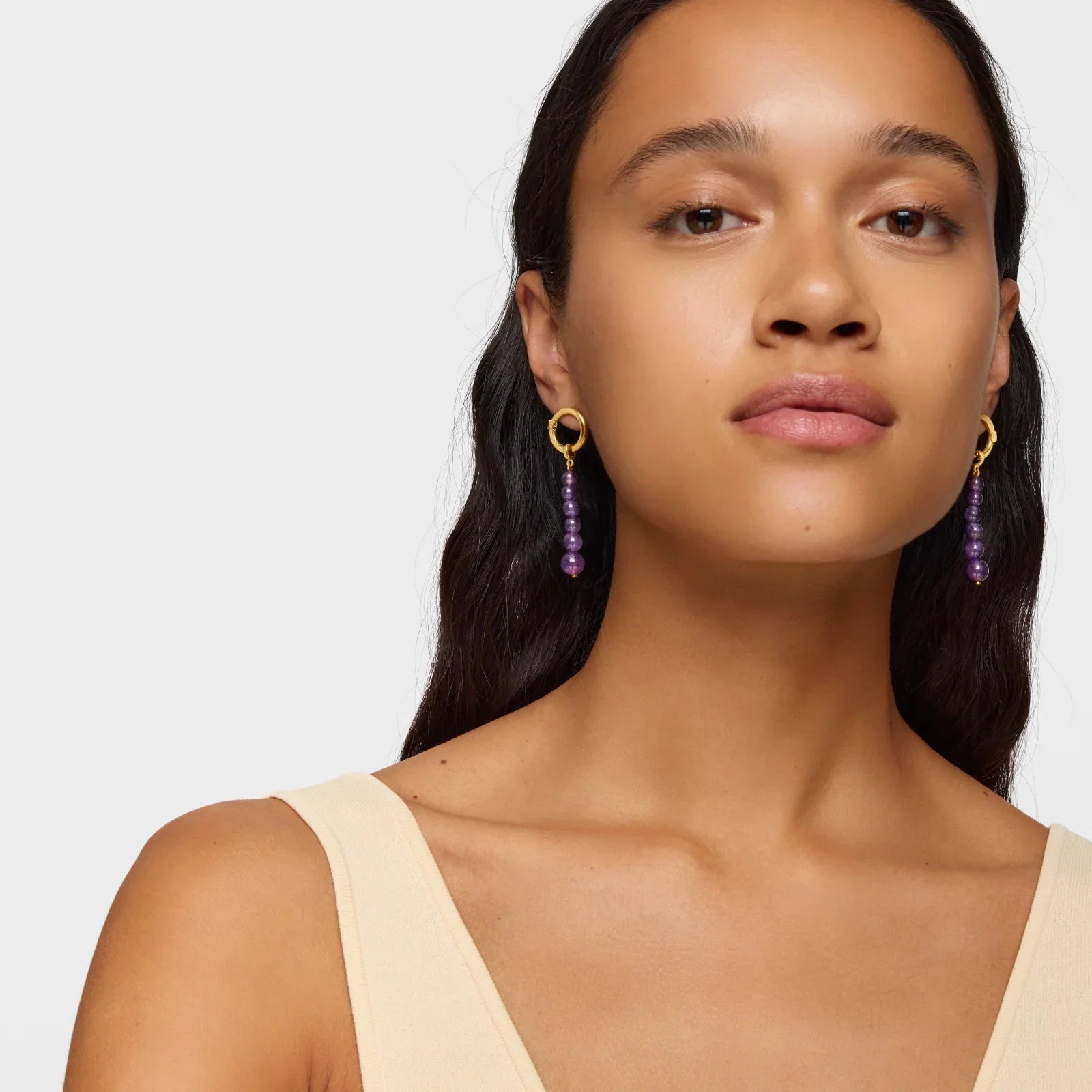 אישה עונדת עגילי זהב עם חרוזים סגולים, תכשיטים אופנתיים ב-CHOZEN