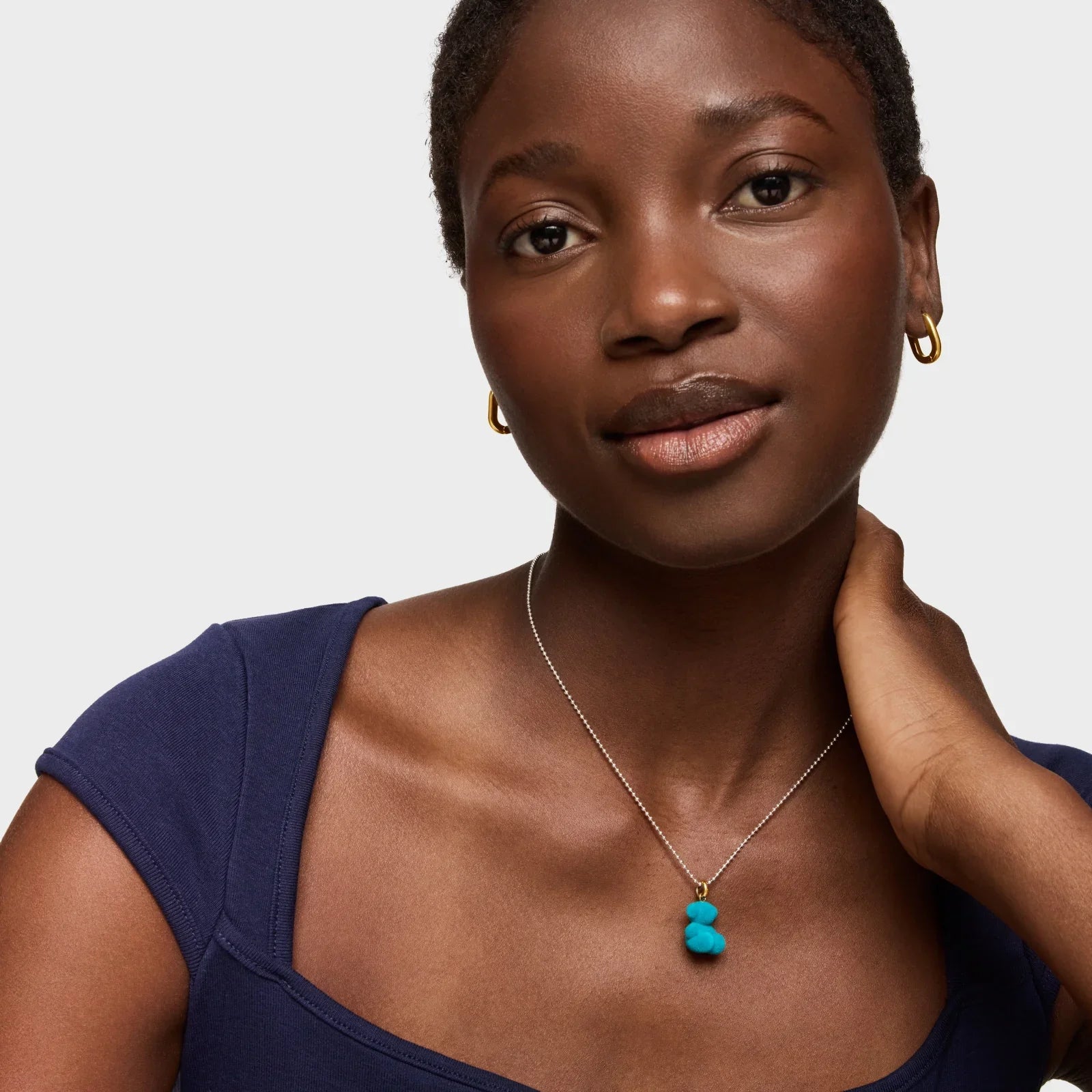 אישה עם שמלה כחולה, עונדת שרשרת עם תליון טורקיז ועגילי זהב, צילום ל-CHOZEN מבית אלפא