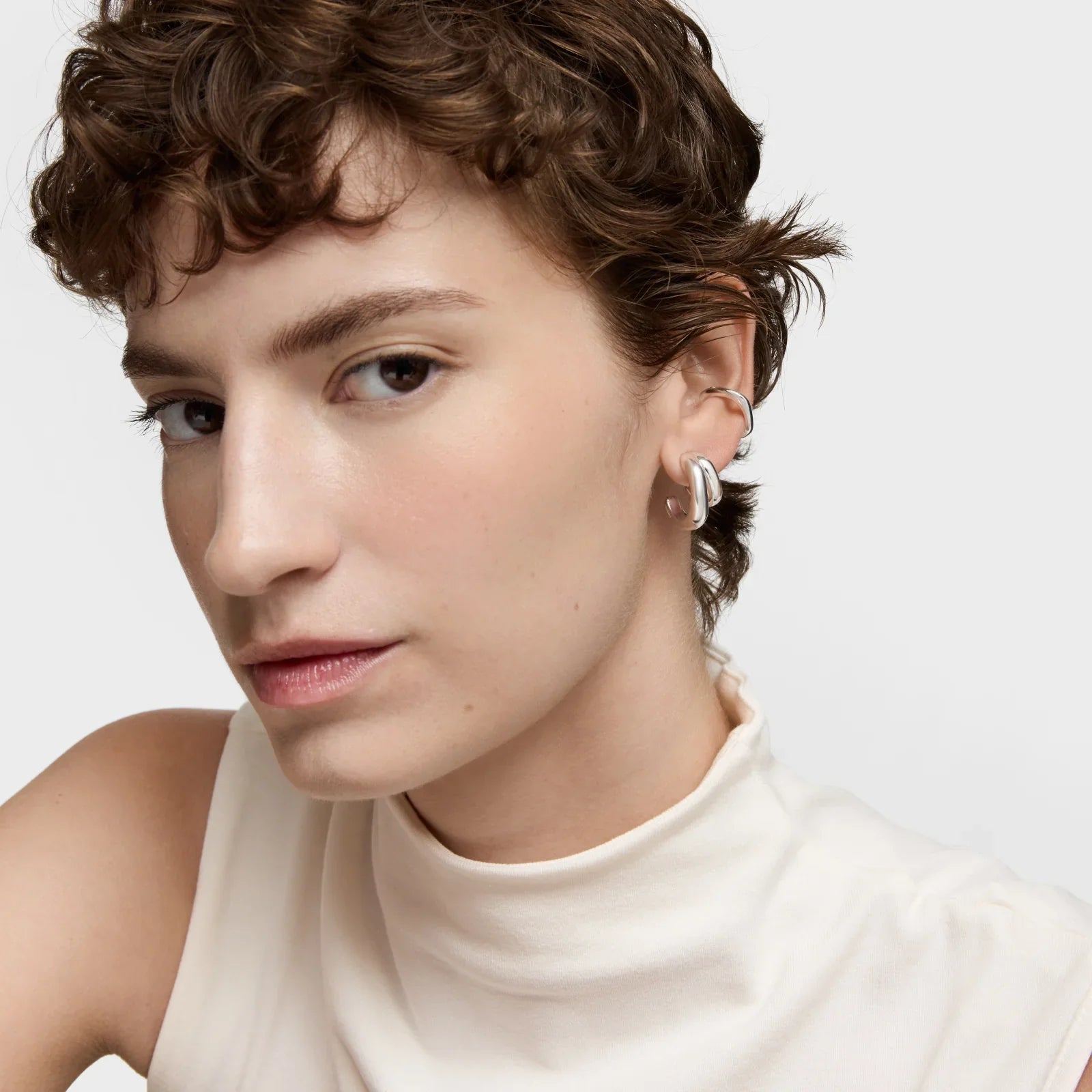 אישה עם שיער קצר עונדת עגילי כסף מעוצבים, צילום תקריב, CHOZEN תכשיטים אופנתיים