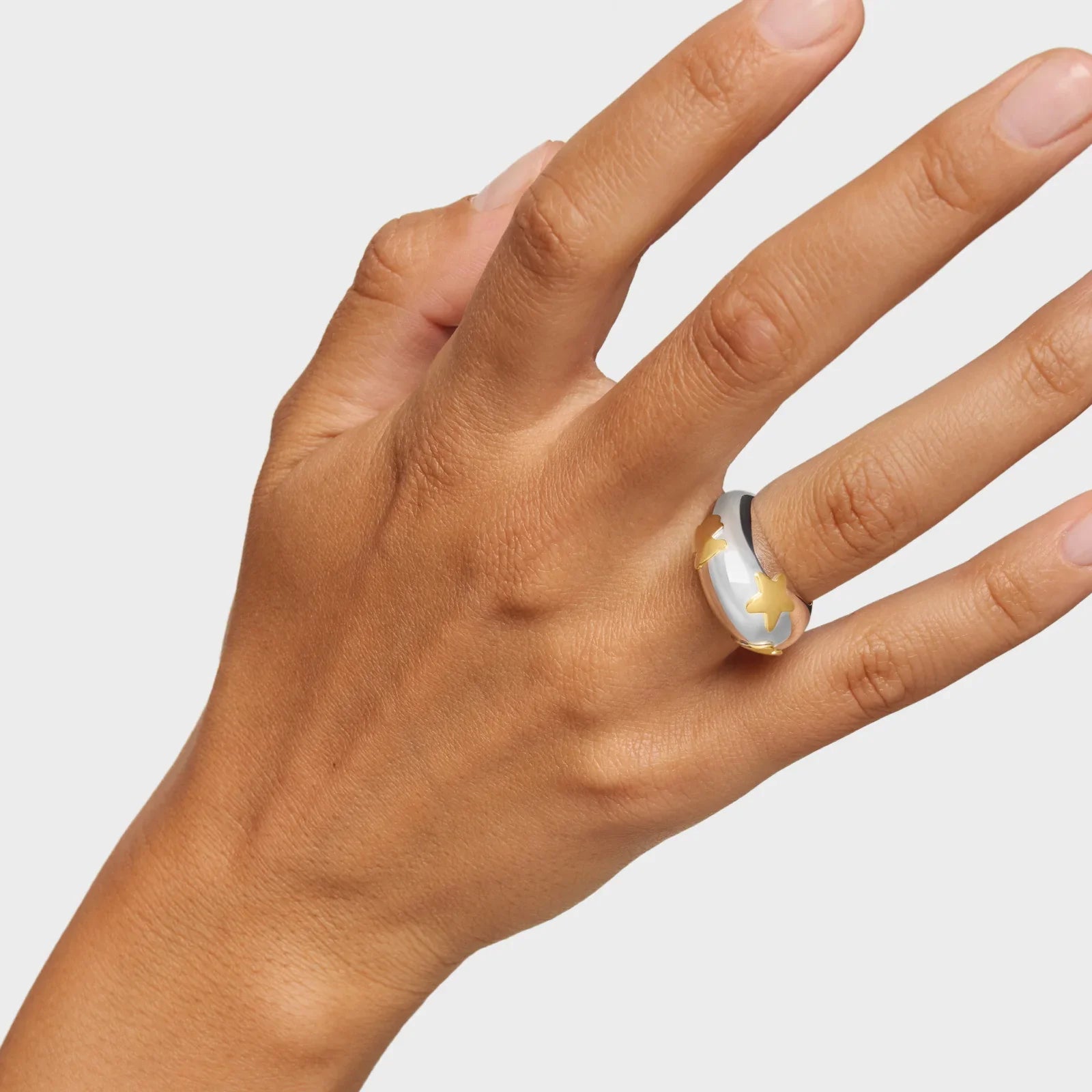 יד עונדת טבעת עבה מכסף עם כוכבים זהובים, צילום מוצר תכשיטים CHOZEN