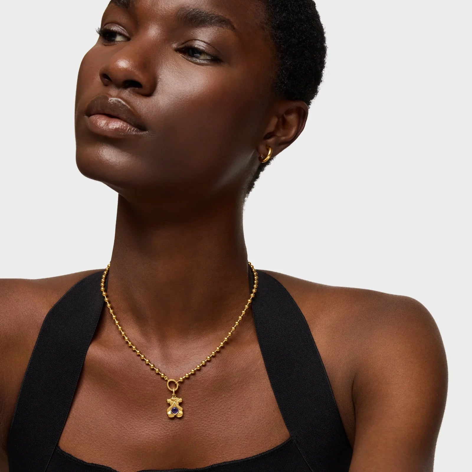 דוגמנית עונדת שרשרת זהב עם תליון על רקע לבן, תכשיטים יוקרתיים CHOZEN