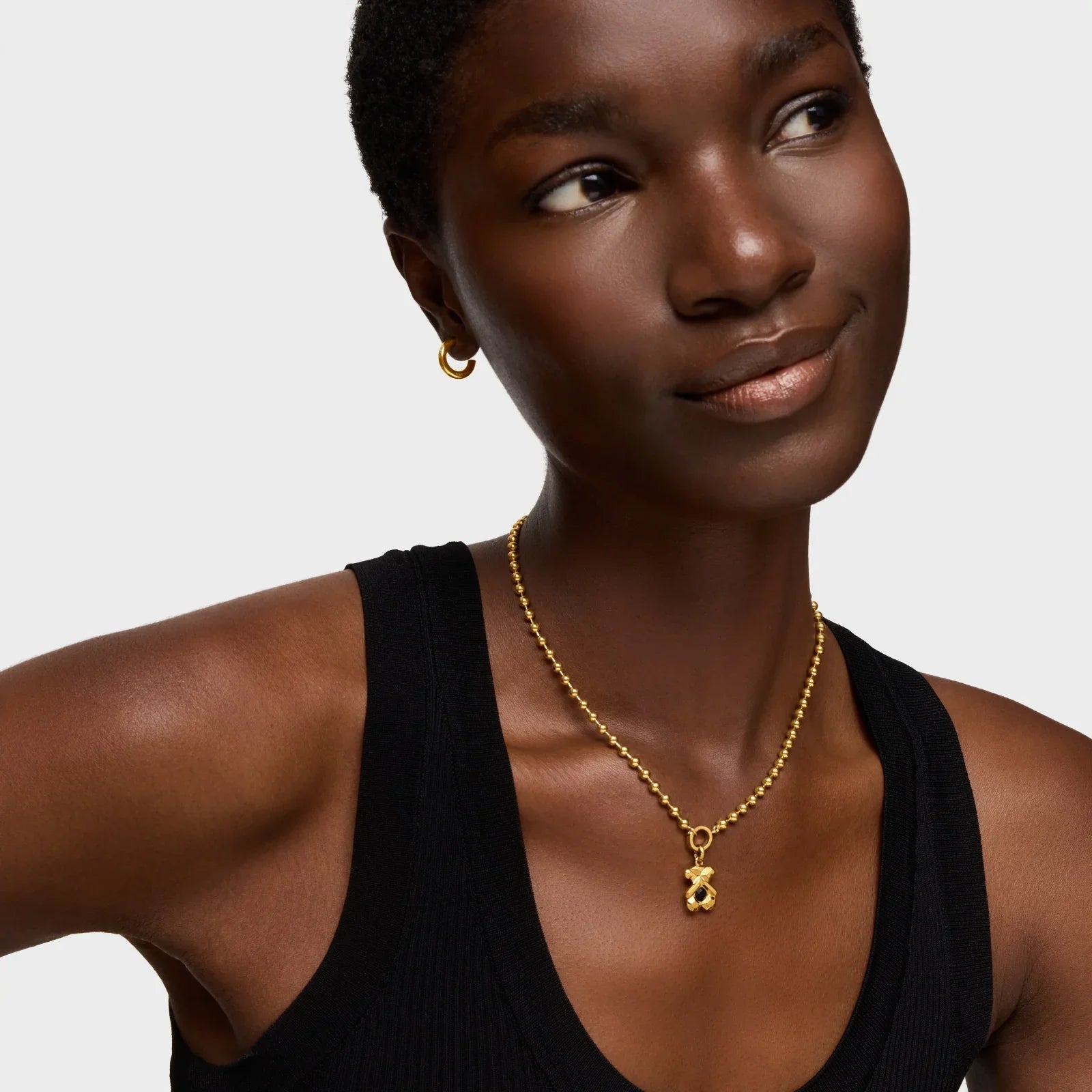 דוגמנית עם גופיה שחורה, עונדת עגיל זהב ושרשרת זהב אופנתית, CHOZEN תכשיטים יוקרתיים