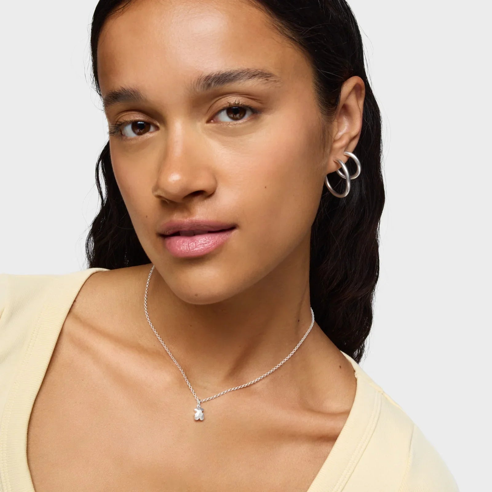 אישה עונדת עגילים וכדור כסף ותליון שרשרת דובי מכסף, צילום תכשיטי בסטייל CHOZEN