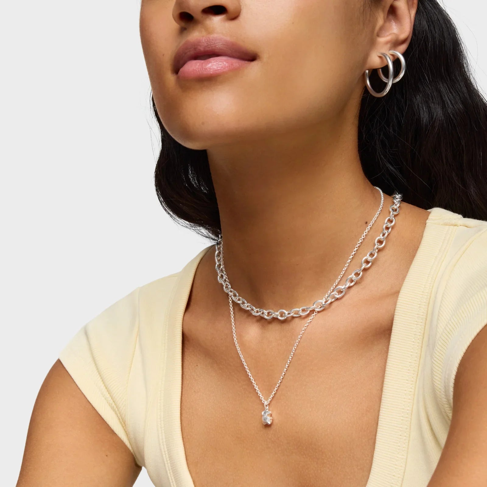 אישה עונדת עגילים וכמה שרשראות כסף, תכשיטים אופנתיים של CHOZEN