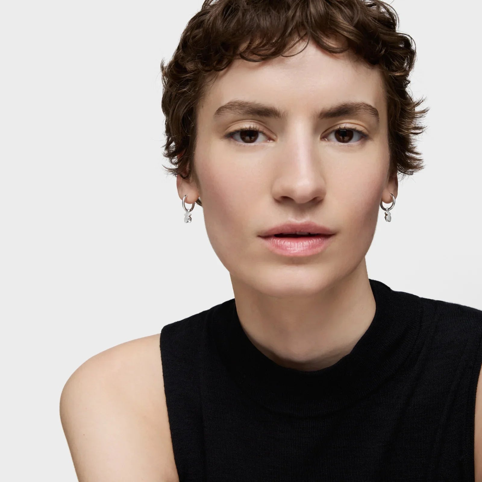 דוגמנית עם חולצה שחורה ועגילי כסף צמודים, צולמה בסטודיו למותגי אופנה CHOZEN