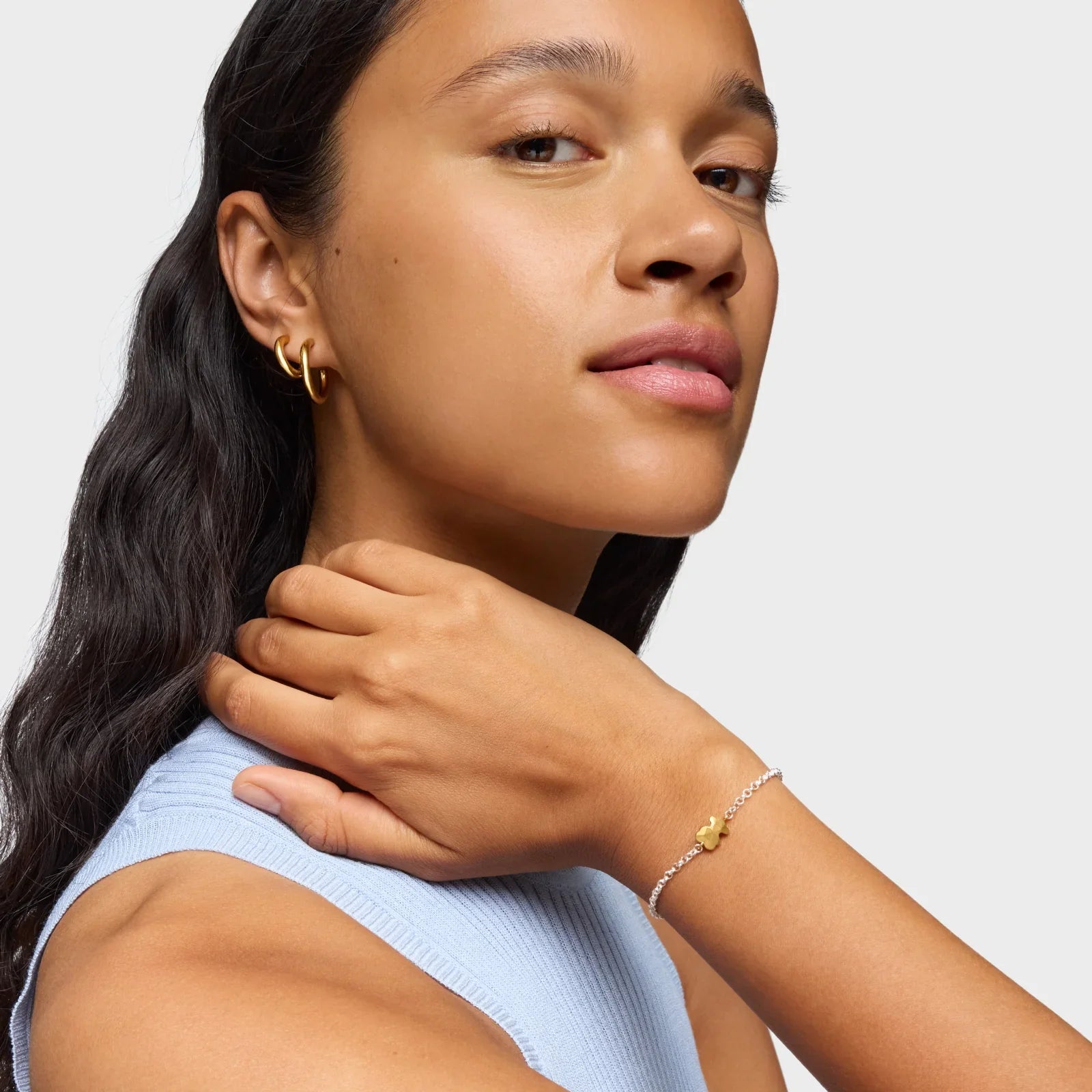 אישה עונדת עגילים מזהב וצמיד עדין, תכשיטים יוקרתיים מבית CHOZEN