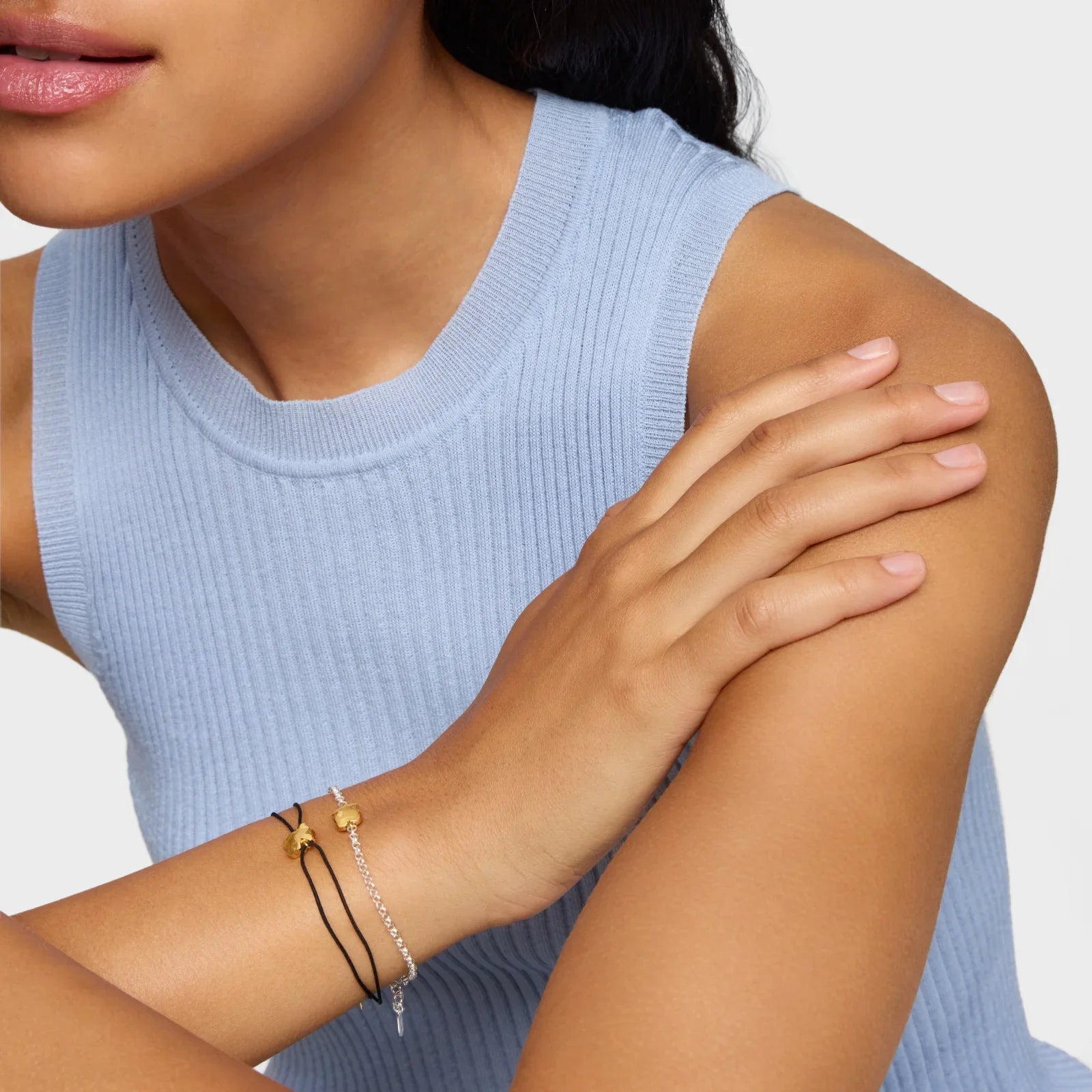 אישה עם גופיה כחולה עונדת צמידי כסף וזהב על רקע לבן, תכשיטי אופנה CHOZEN