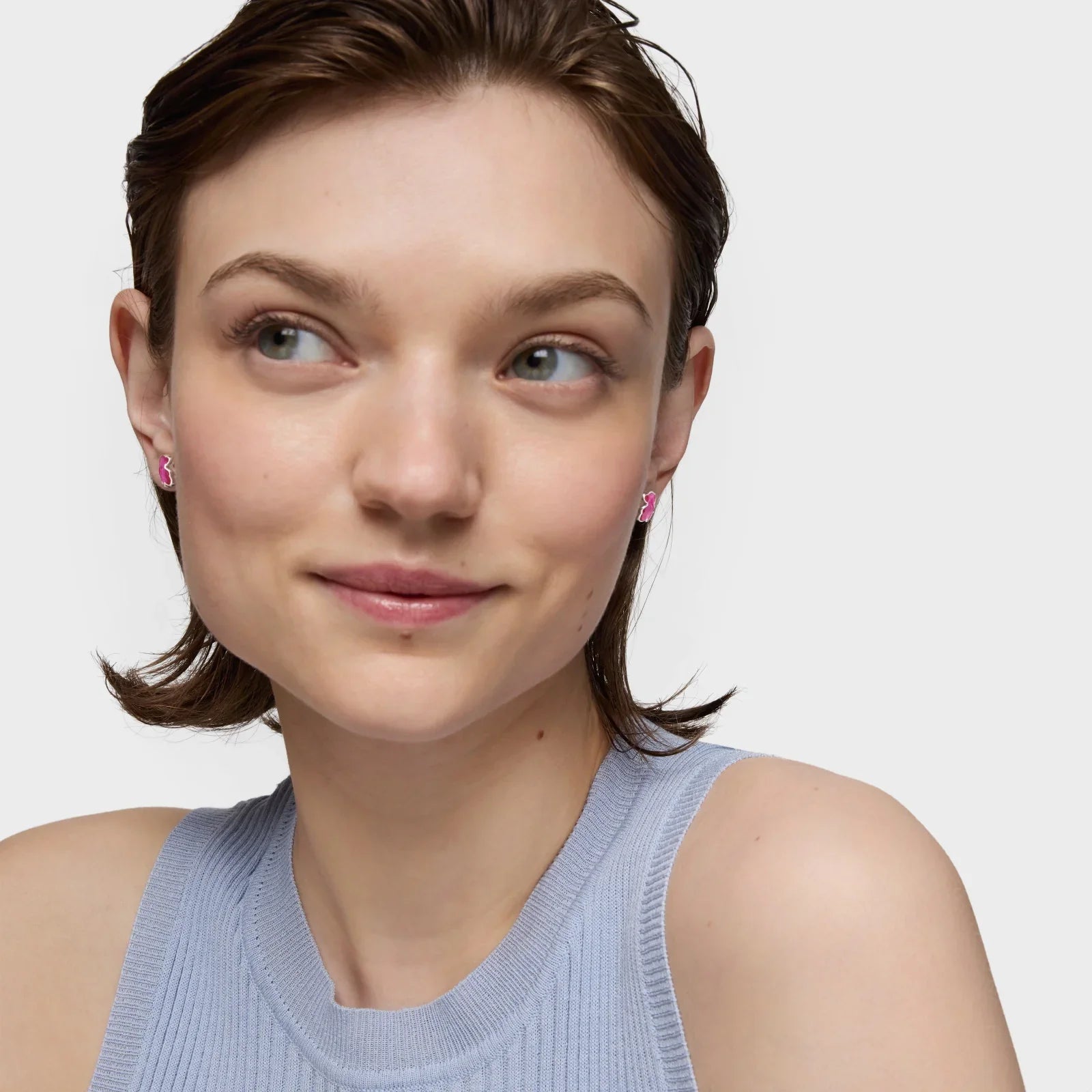 אישה עונדת עגילי פרפר ורודים, מצולמת מקרוב, רקע לבן חלק, CHOZEN מותגים מובילים