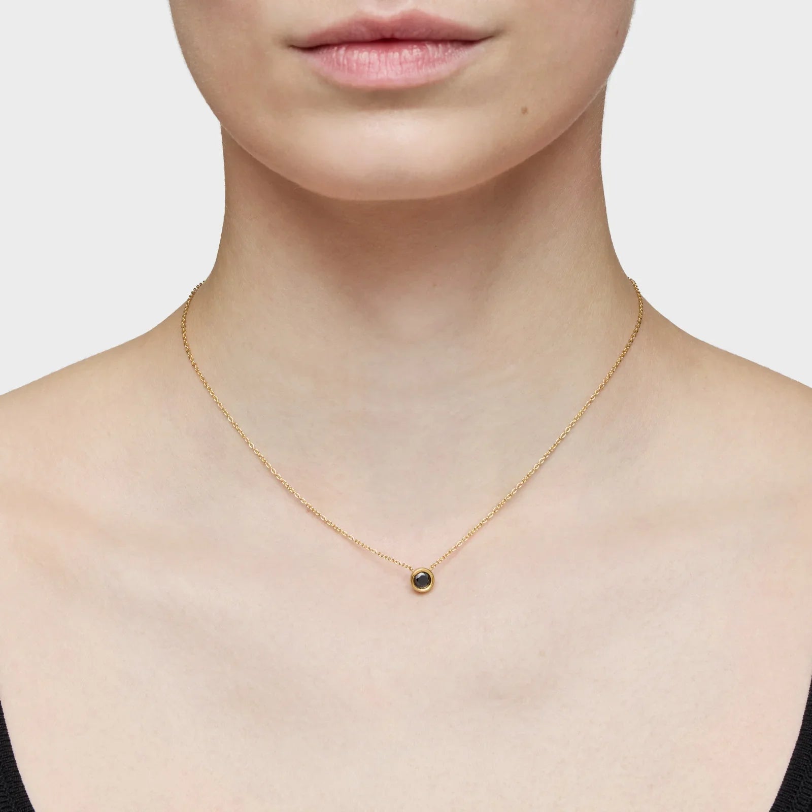 שרשרת זהב עדינה עם תליון שחור על צוואר דוגמנית, מבית המותגים של CHOZEN
