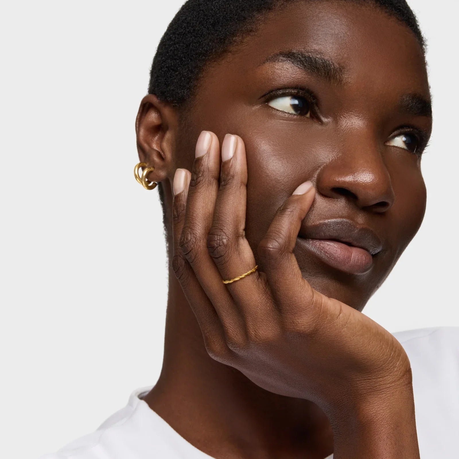 אישה עם עגיל זהב וטבעת עדינה על רקע לבן, תכשיטים יוקרתיים CHOZEN