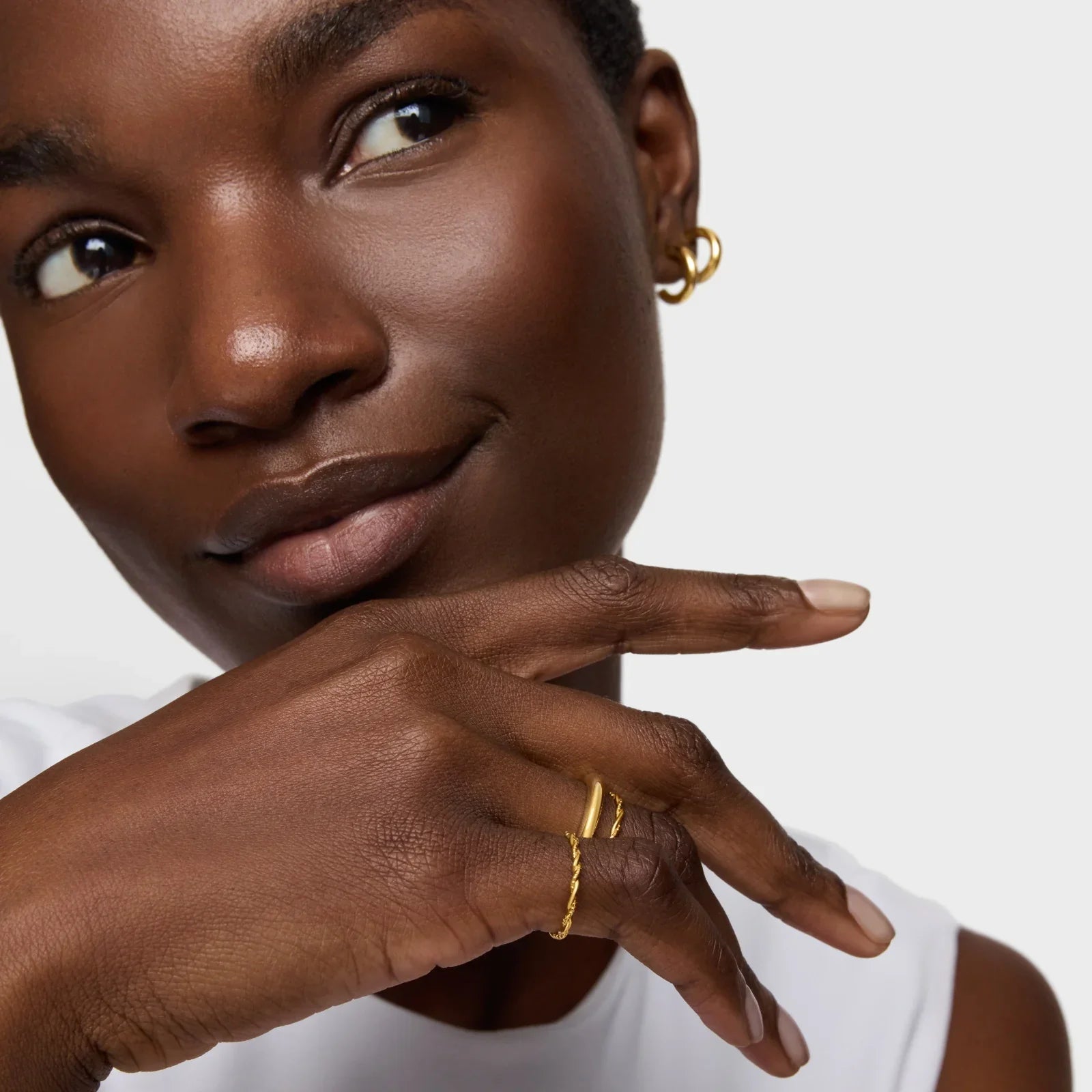 אישה עונדת תכשיטי זהב עדינים, עגילים וטבעות, צילום תקריב מסדרת המותגים של CHOZEN