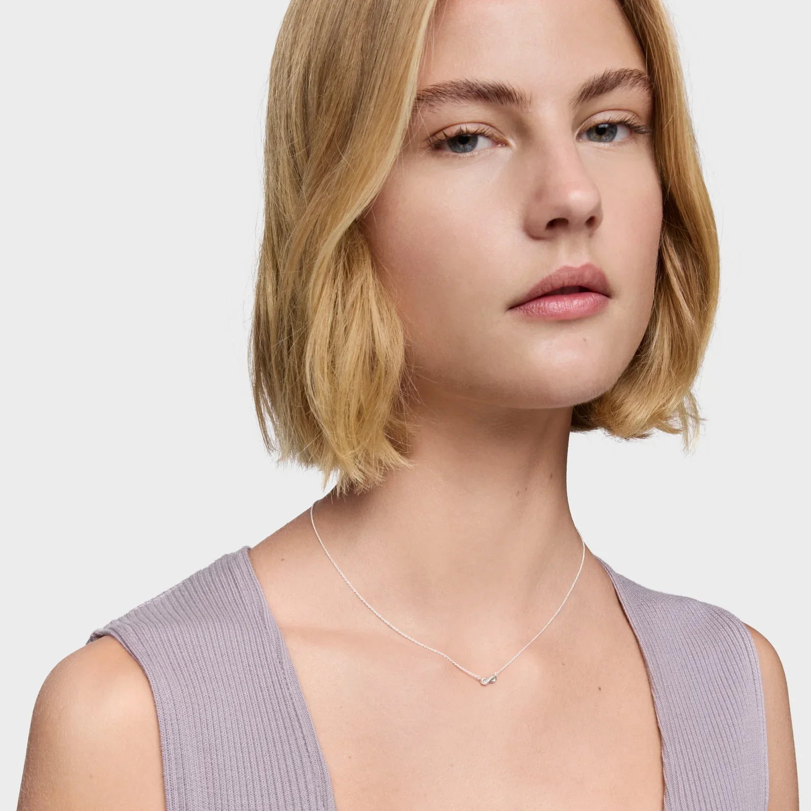 אישה עם שיער בלונדיני קצר עונדת שרשרת דקה ועדינה, צילום לקטלוג תכשיטים CHOZEN
