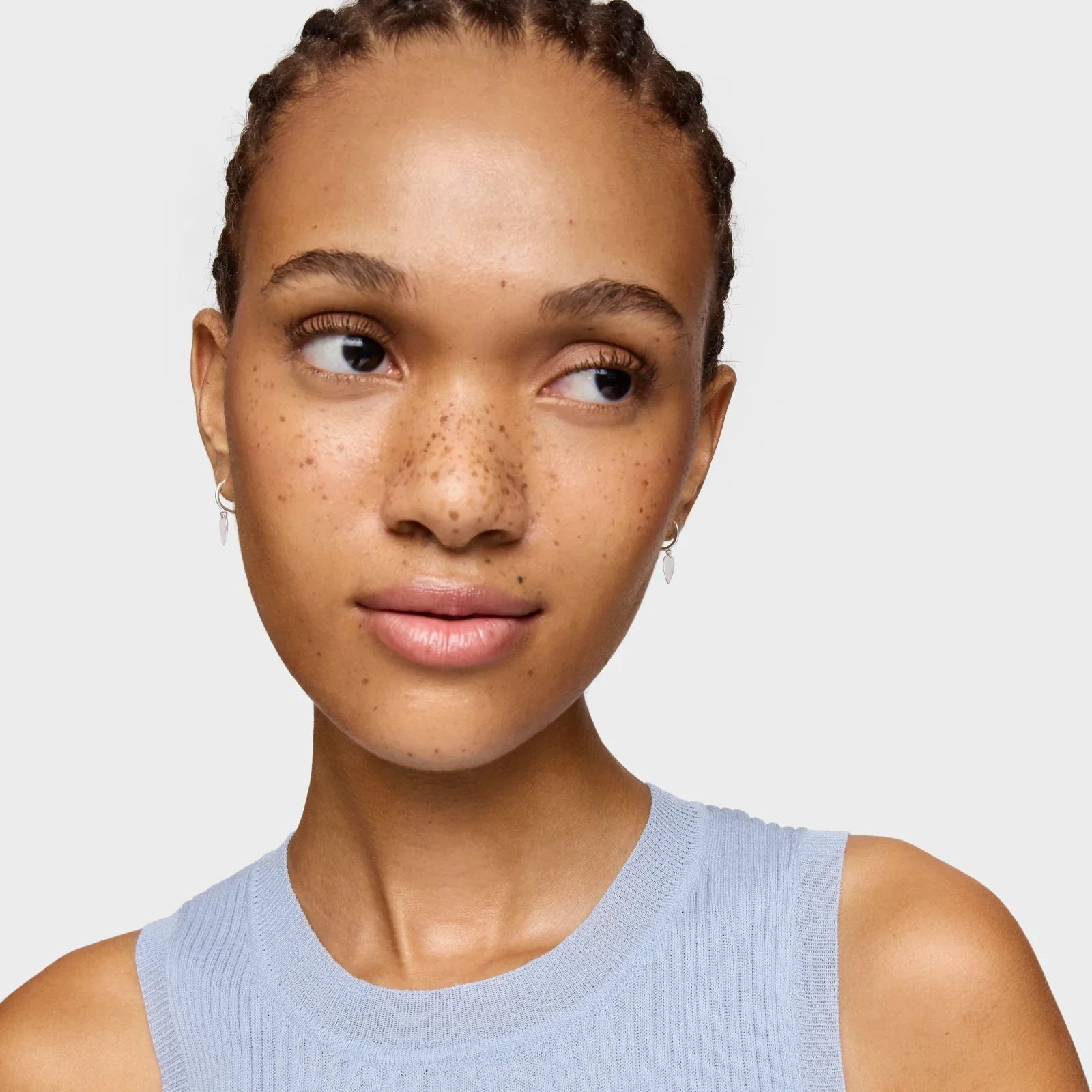 אישה צעירה עם שיער קלוע עגילים קטנים ולבוש טופ כחול, צילום תדמית CHOZEN