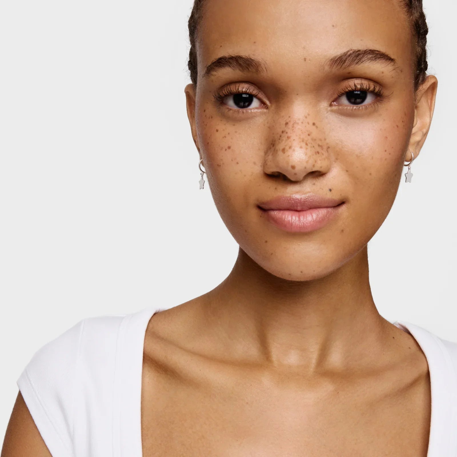 אישה עם עגילי כסף מעוצבים מבית קבוצת אלפא, רקע לבן, צילום תקריב CHOZEN