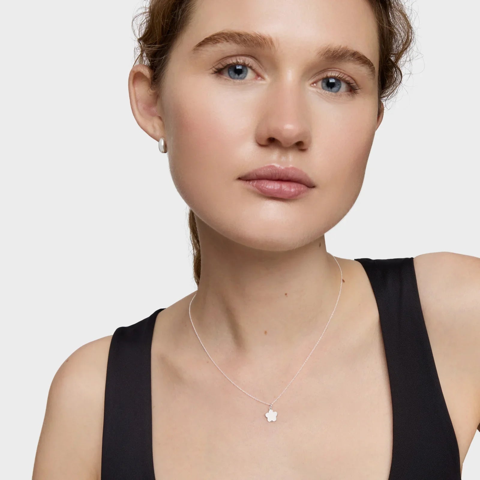 דוגמנית עונדת שרשרת כסף עם תליון פרח ועגילי פנינה, צילום תכשיטים CHOZEN