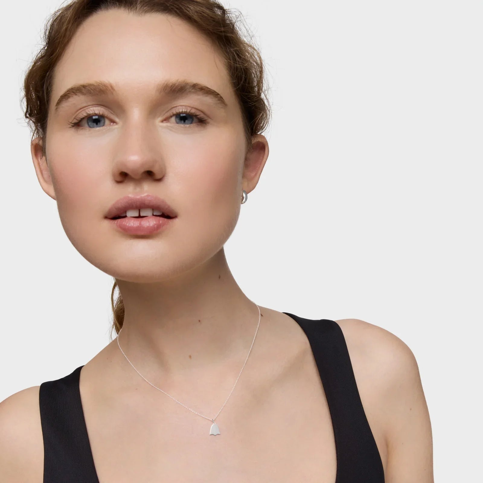 דוגמנית עונדת שרשרת כסף עדינה על רקע לבן, תכשיטים יוקרתיים CHOZEN