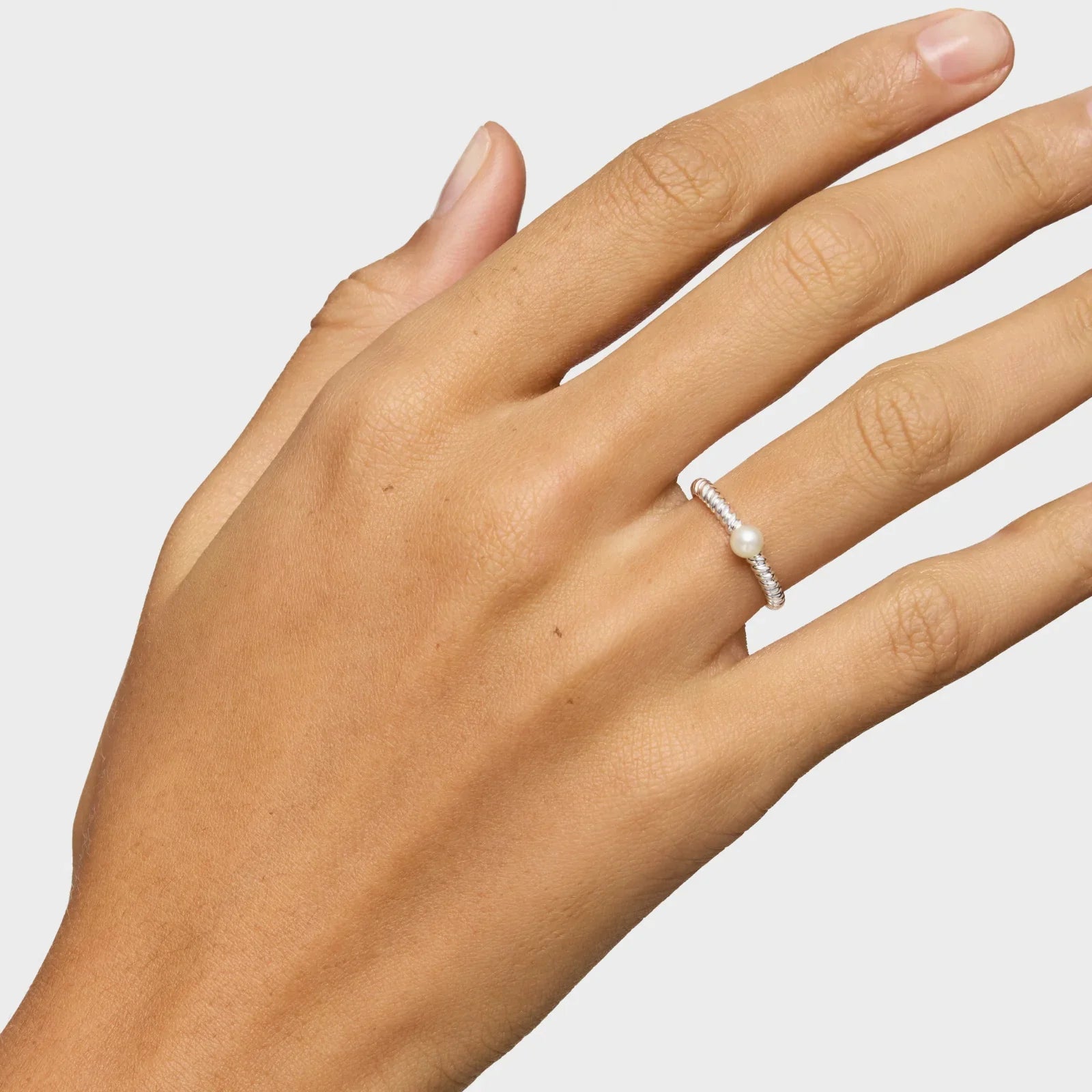 יד עם טבעת כסף עדינה ואבן פנינה על רקע לבן, תכשיט יוקרתי מבית CHOZEN