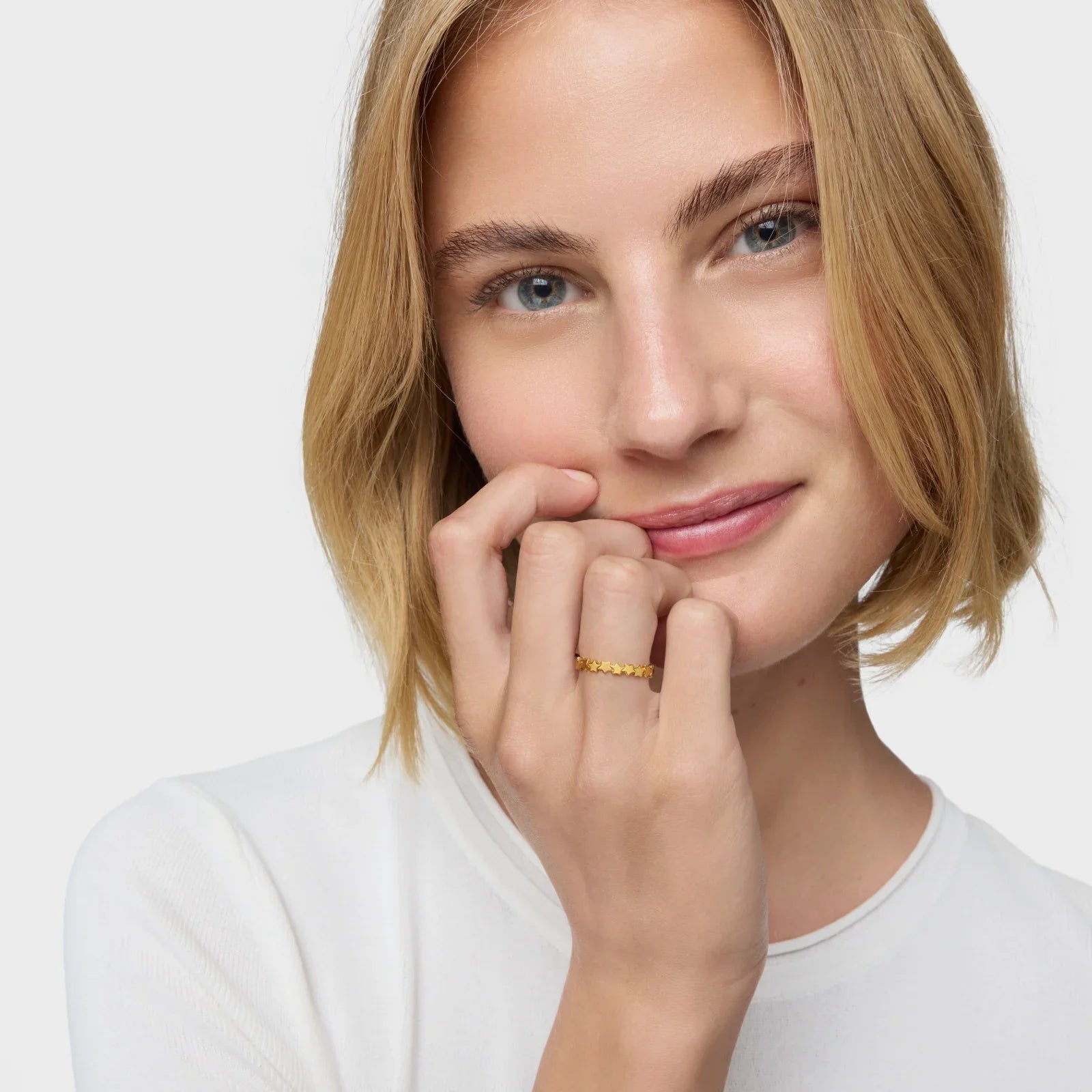 אישה עם שיער בלונדיני קצר עונדת טבעת זהב עדינה, תכשיטים יוקרתיים מבית CHOZEN