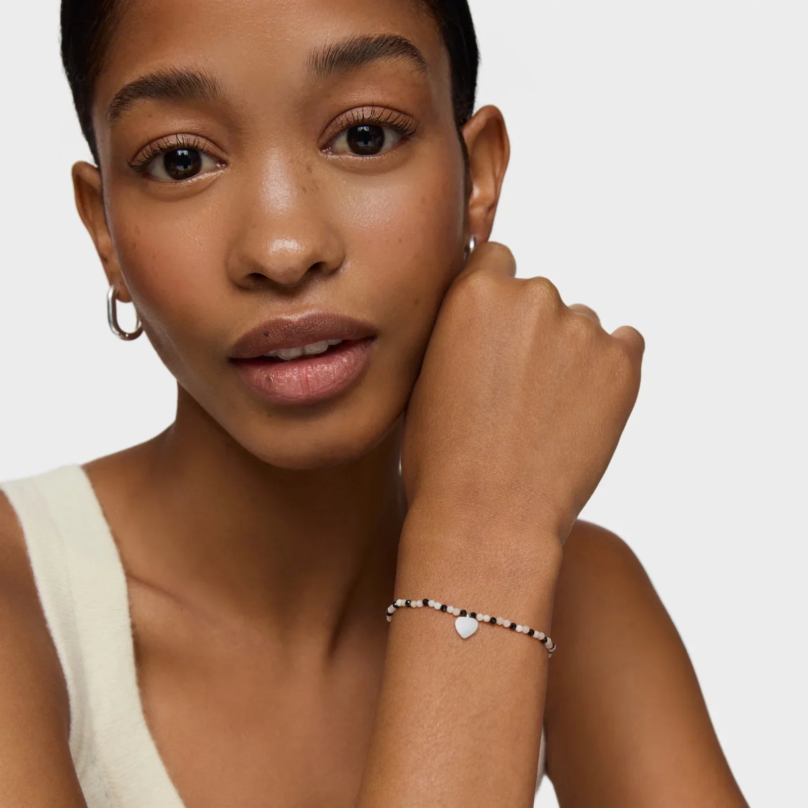 אישה עונדת צמיד כסף דק עם תליון לב, תכשיטי אופנה CHOZEN