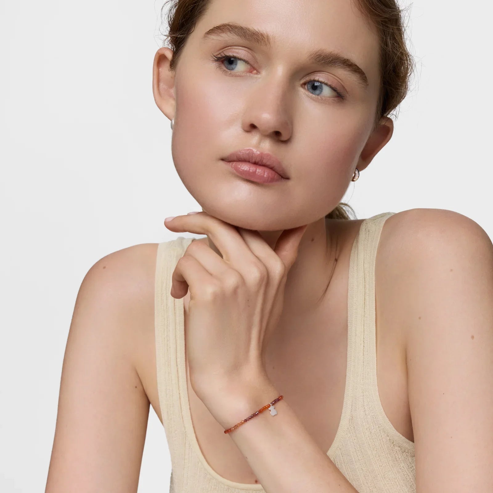 דוגמנית לובשת גופייה בז׳ ותכשיט צמיד עדין, צילום קמפיין תכשיטים CHOZEN