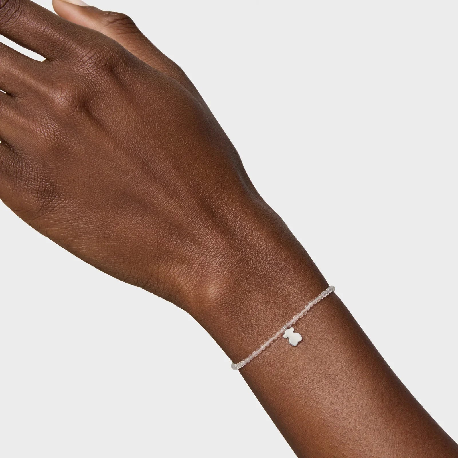 יד עם צמיד עדין CHOZEN, חרוזים לבנים ותליון קטן, רקע לבן