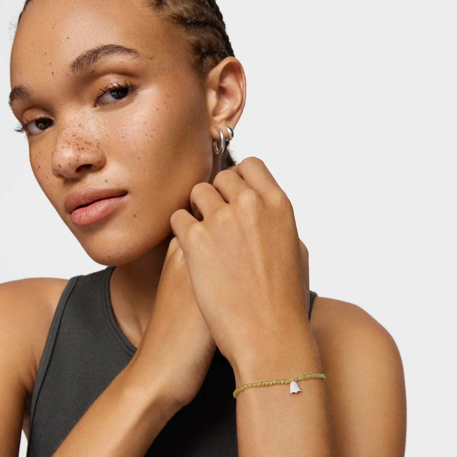 אישה עם עגילים צמודים לובשת צמיד עדין של CHOZEN, רקע לבן, תכשיטים יוקרתיים