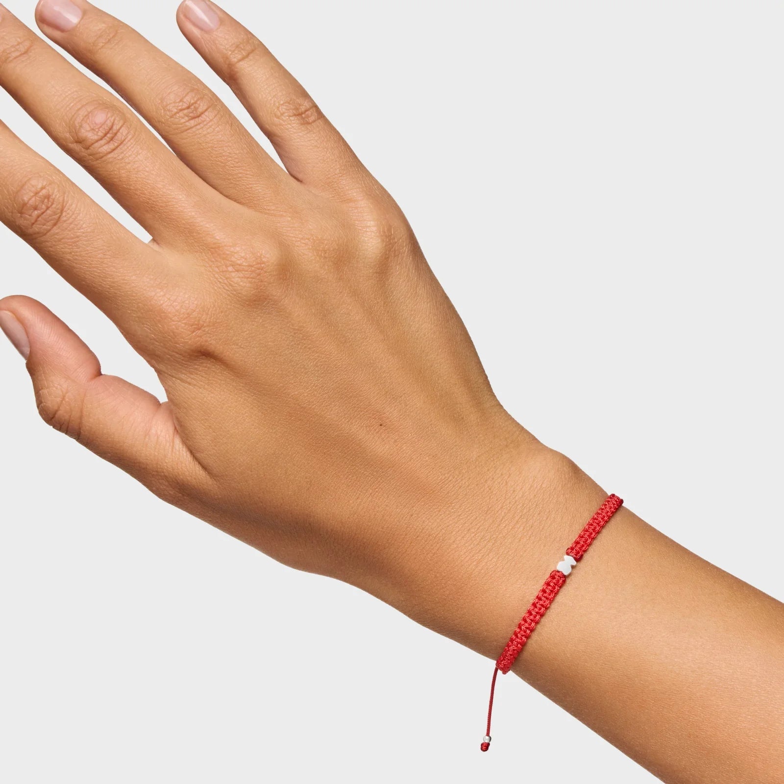 צמיד חוט אדום עם תליון קטן על יד אישה, מוצר אופנה CHOZEN מבית קבוצת אלפא