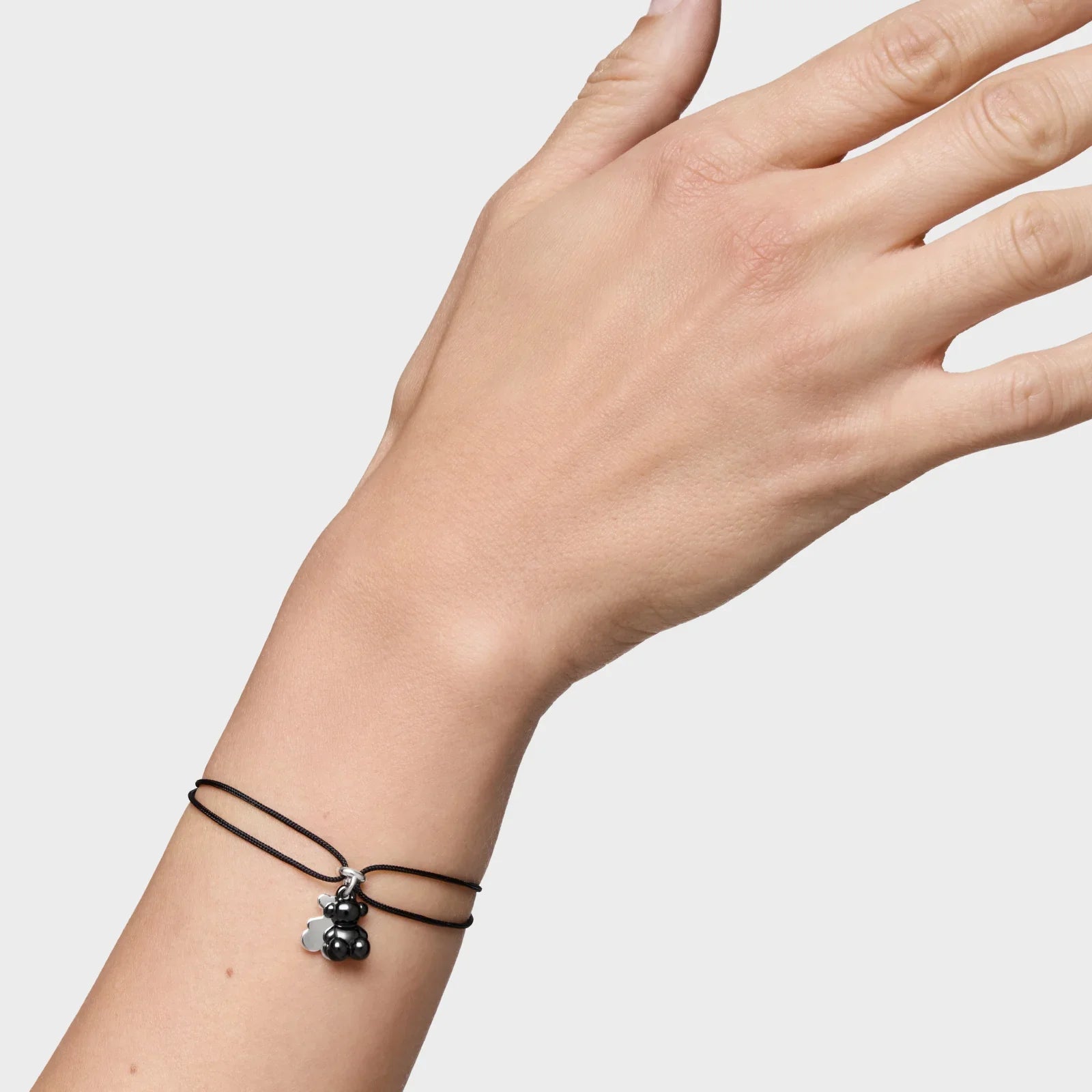 יד עם צמיד חוט שחור ותליון בצורת דובי מחברת CHOZEN, צילום מוצר לתכשיטים יוקרתיים