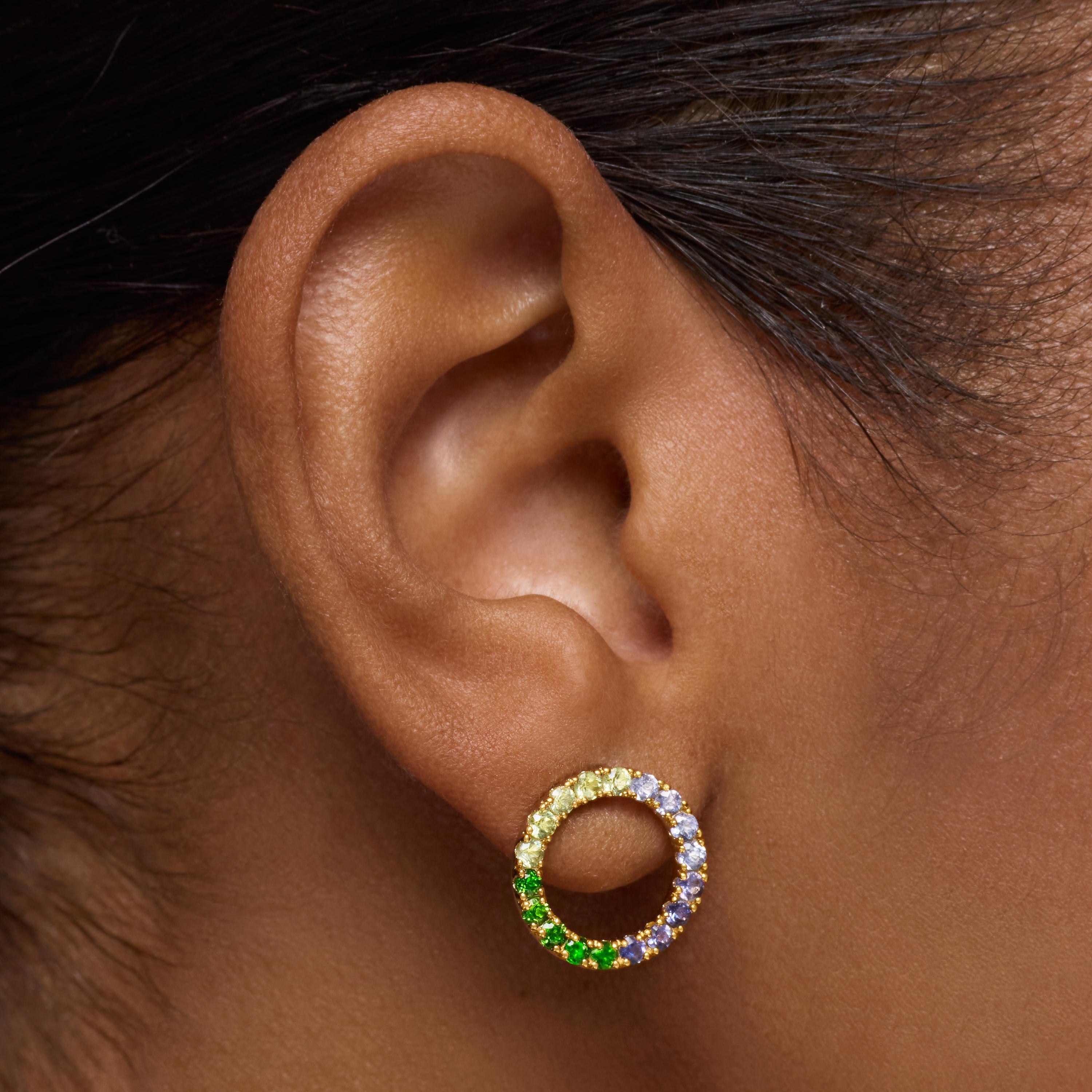 עגיל חישוק זהב בעיצוב עיגול עם אבני חן צבעוניות ירוק כחול וצהוב על אוזן אישה
