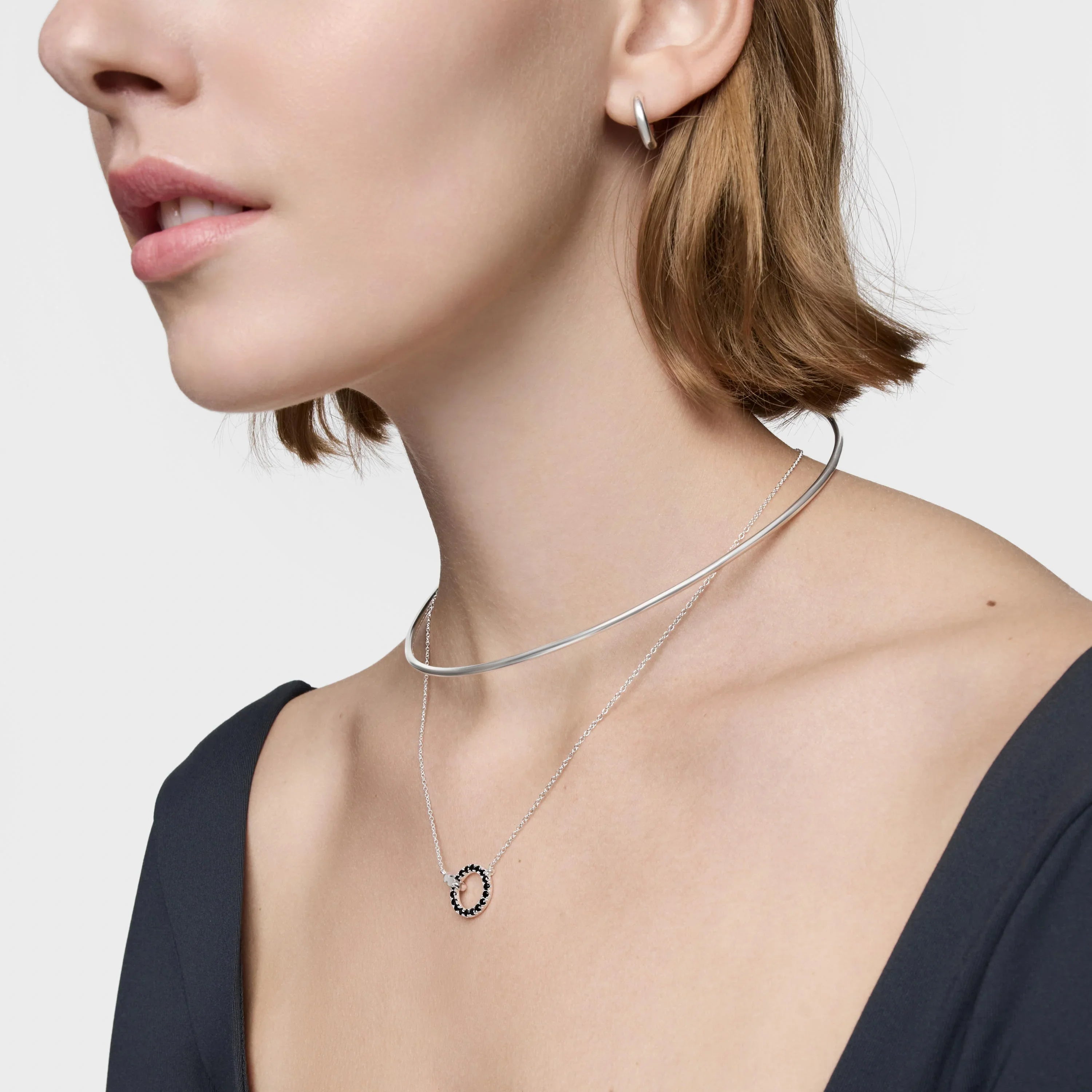 דוגמנית עונדת שרשרת כסף עדינה, שרשרת כסף קשיחה ועגילי כסף קטנים