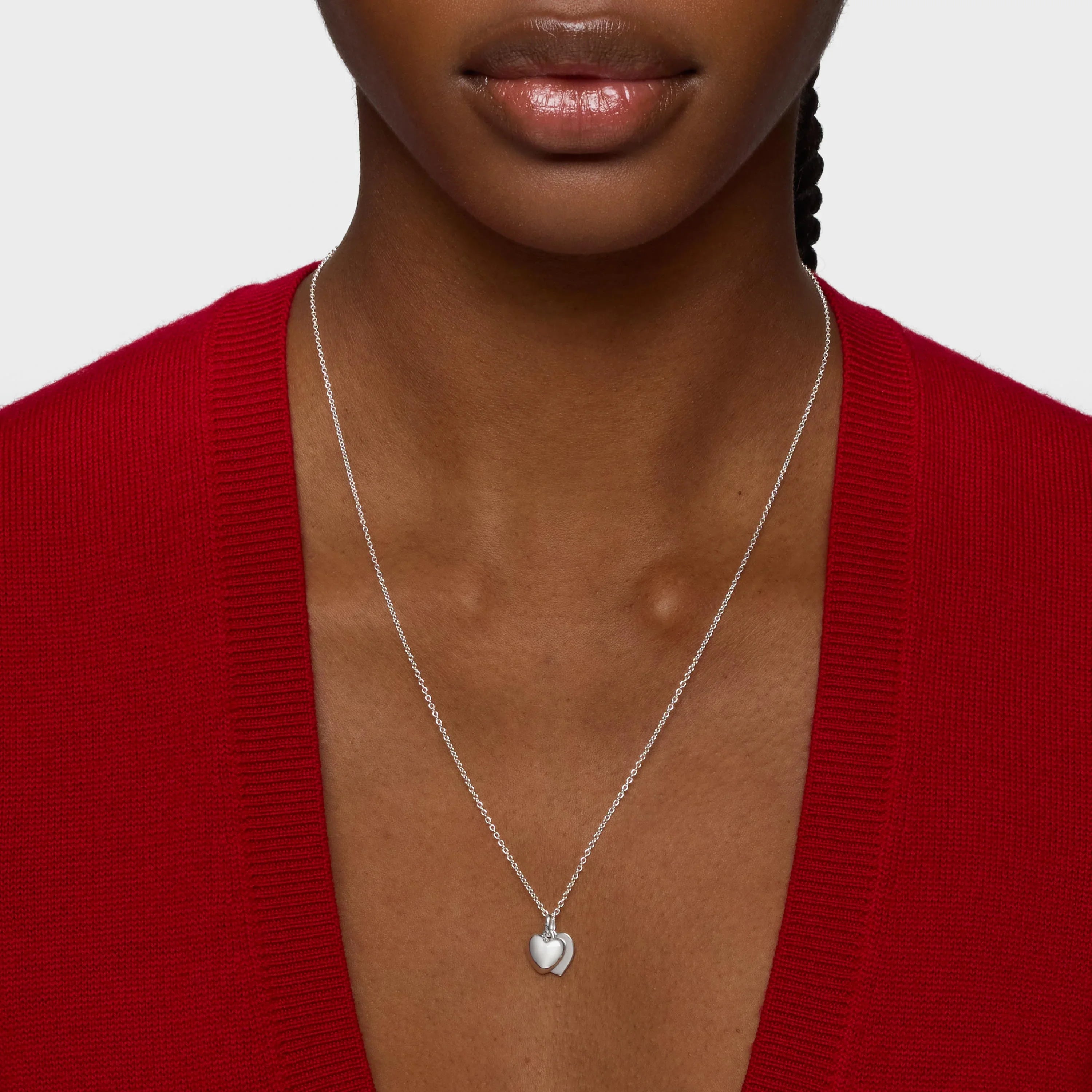 שרשרת כסף עדינה עם תליון לב, על רקע סוודר אדום פתוח