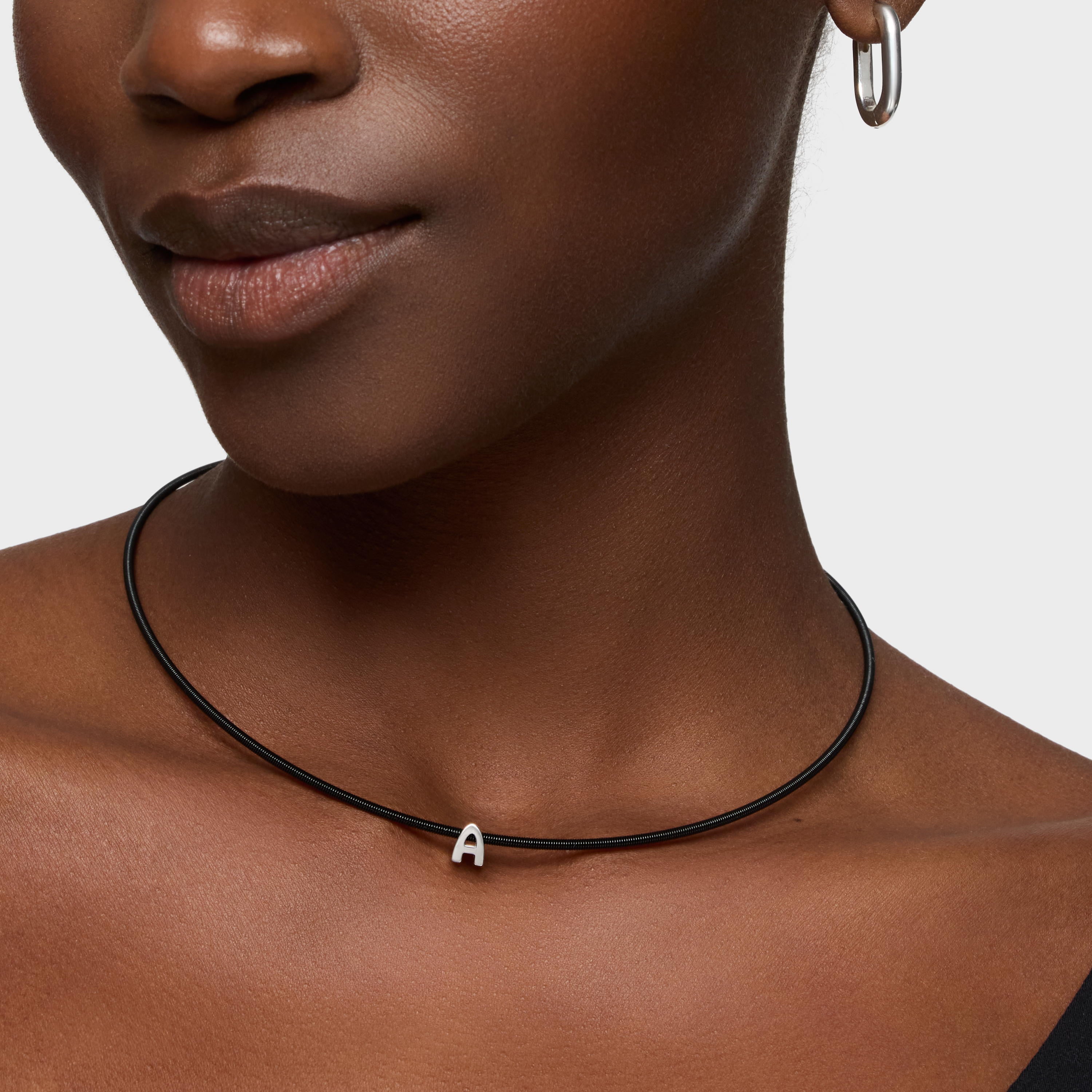 שרשרת שחורה עם תליון אות A כסף על צוואר דוגמנית, עגיל חישוק כסף באוזן