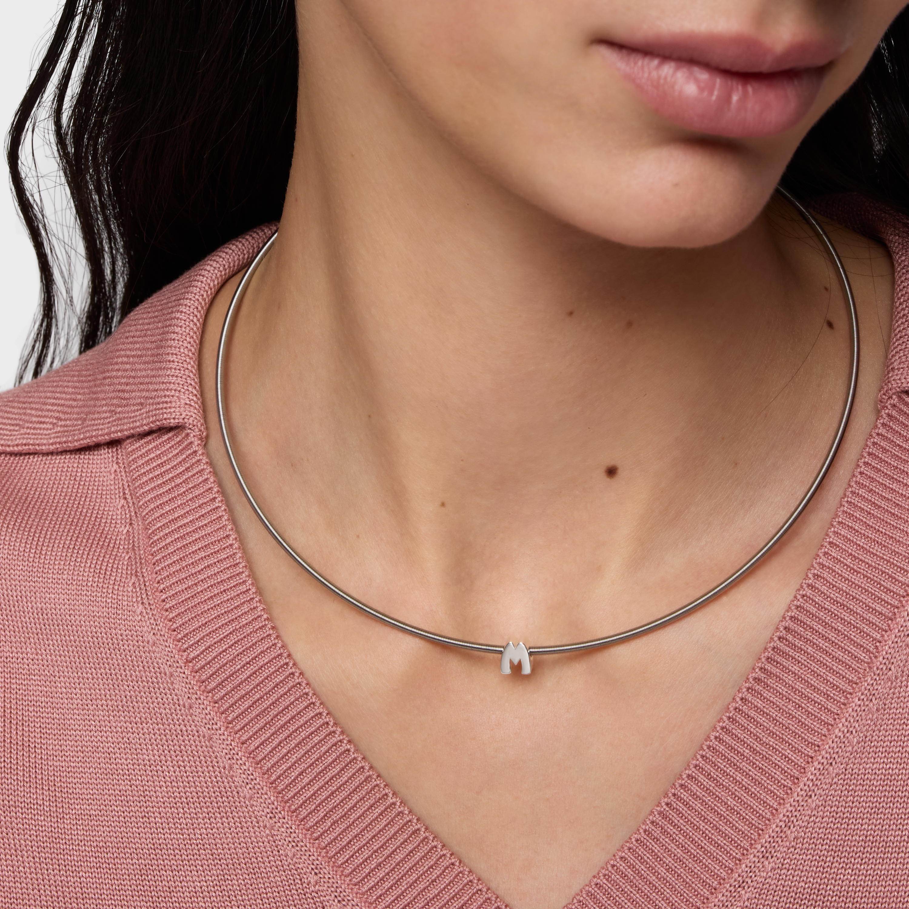 שרשרת כסף עדינה עם תליון אות M, על צוואר של אישה, חולצה ורודה אופנתית