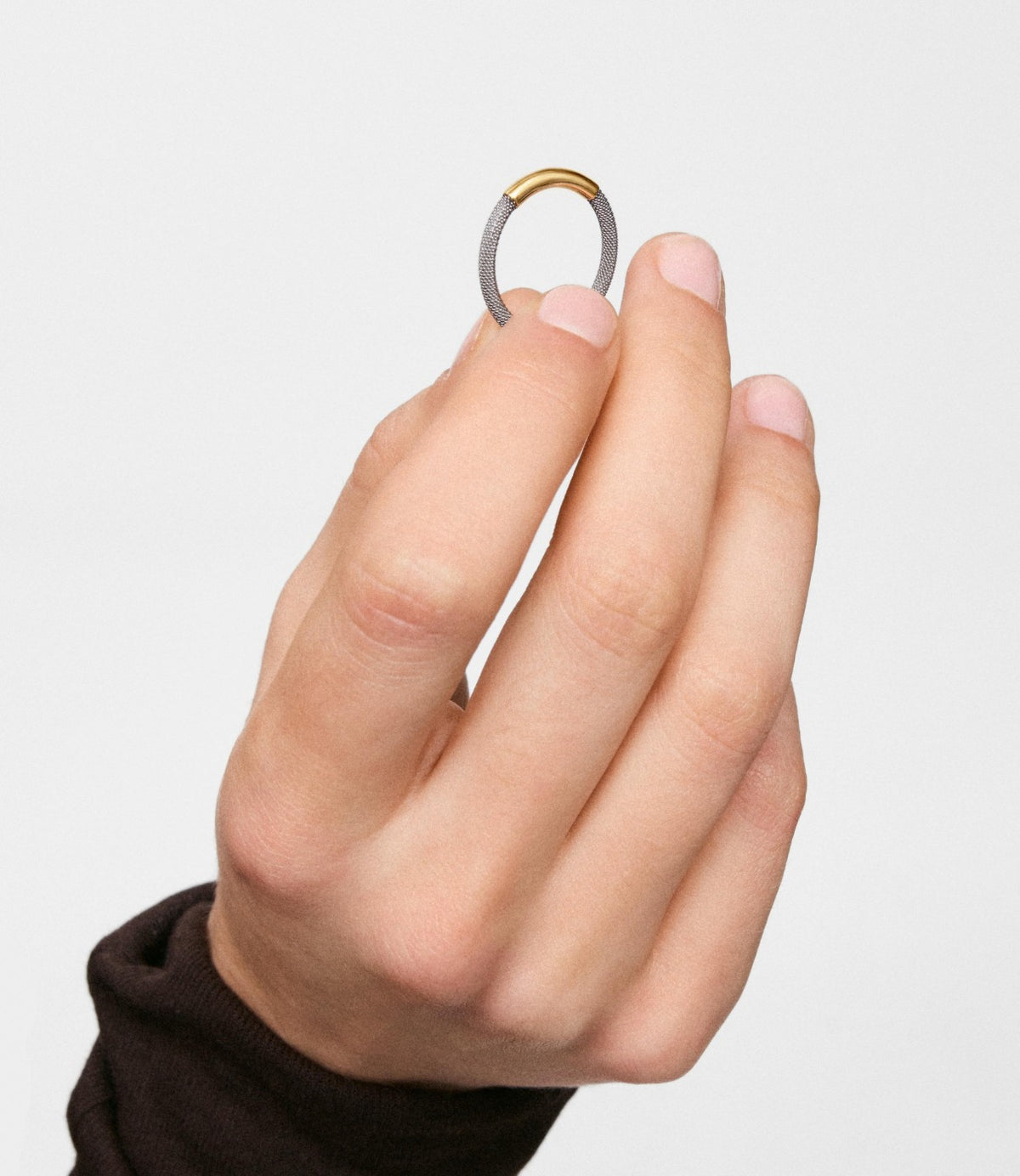תמונה 1: יד מחזיקה טבעת זהב ורשת כסופה מקרוב על רקע בהיר - CHOZEN