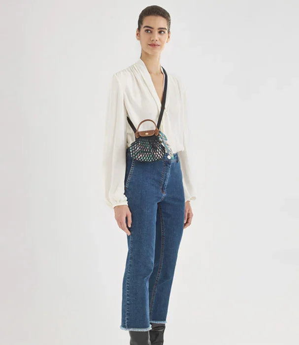 אשה לובשת חולצה לבנה, ג'ינס כחול ותיק מעוצב מבית CHOZEN, אופנה יוקרתית וקז'ואל מודרני