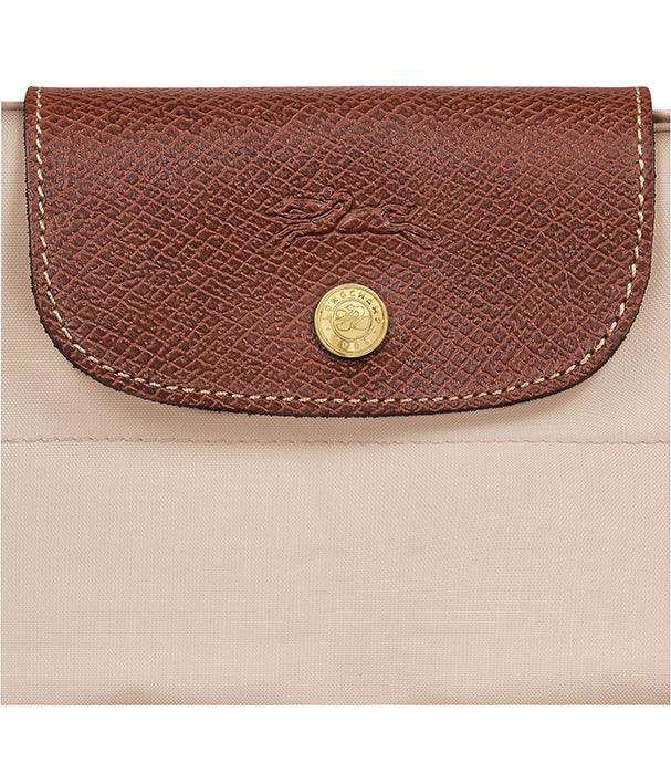 תקריב של תיק יוקרתי בצבע בז' עם סוגר עור חום וכפתור זהב, מבית המותגים ב-CHOZEN